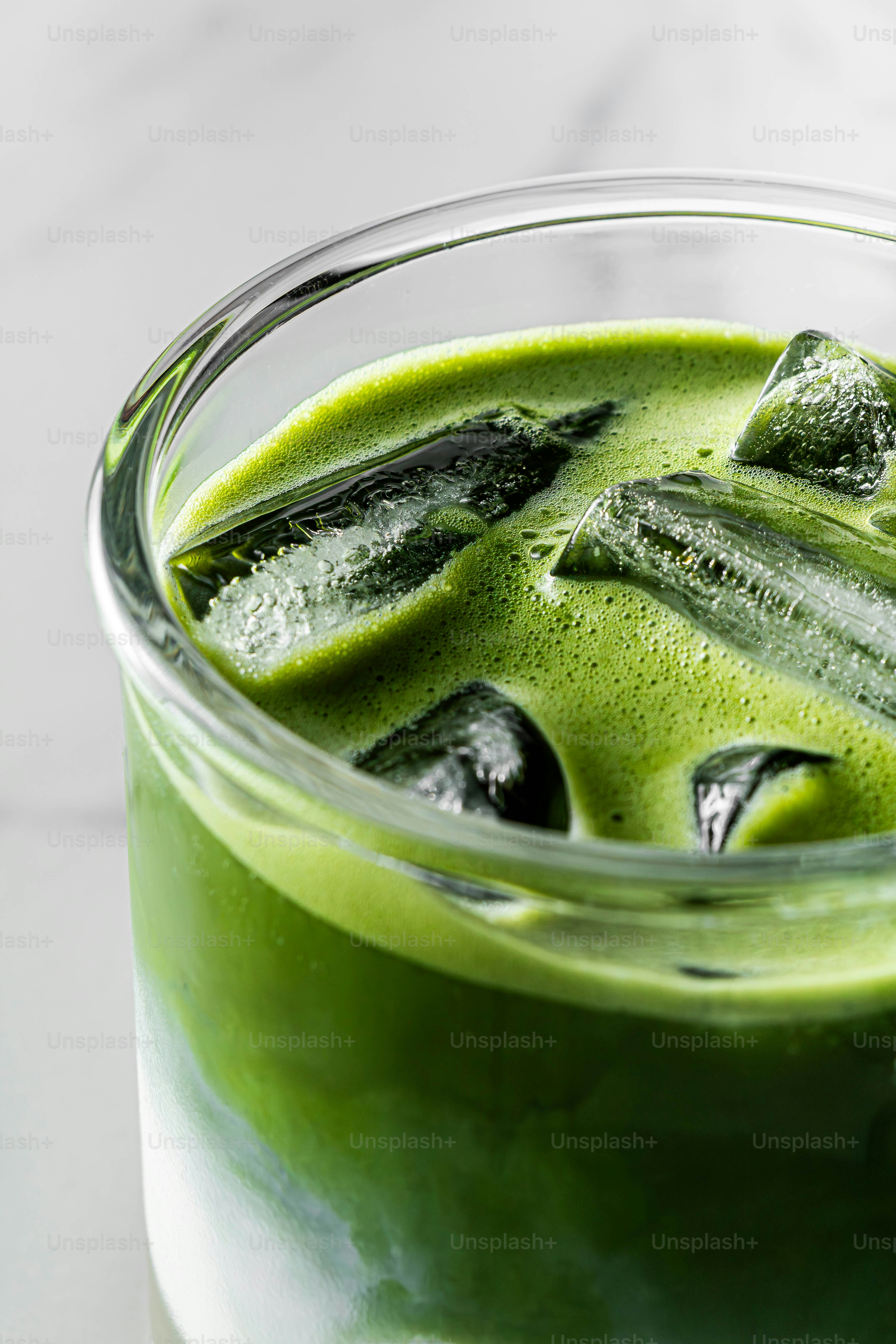 鮮やかな緑色の抹茶のクローズアップで、氷を添えたもの。