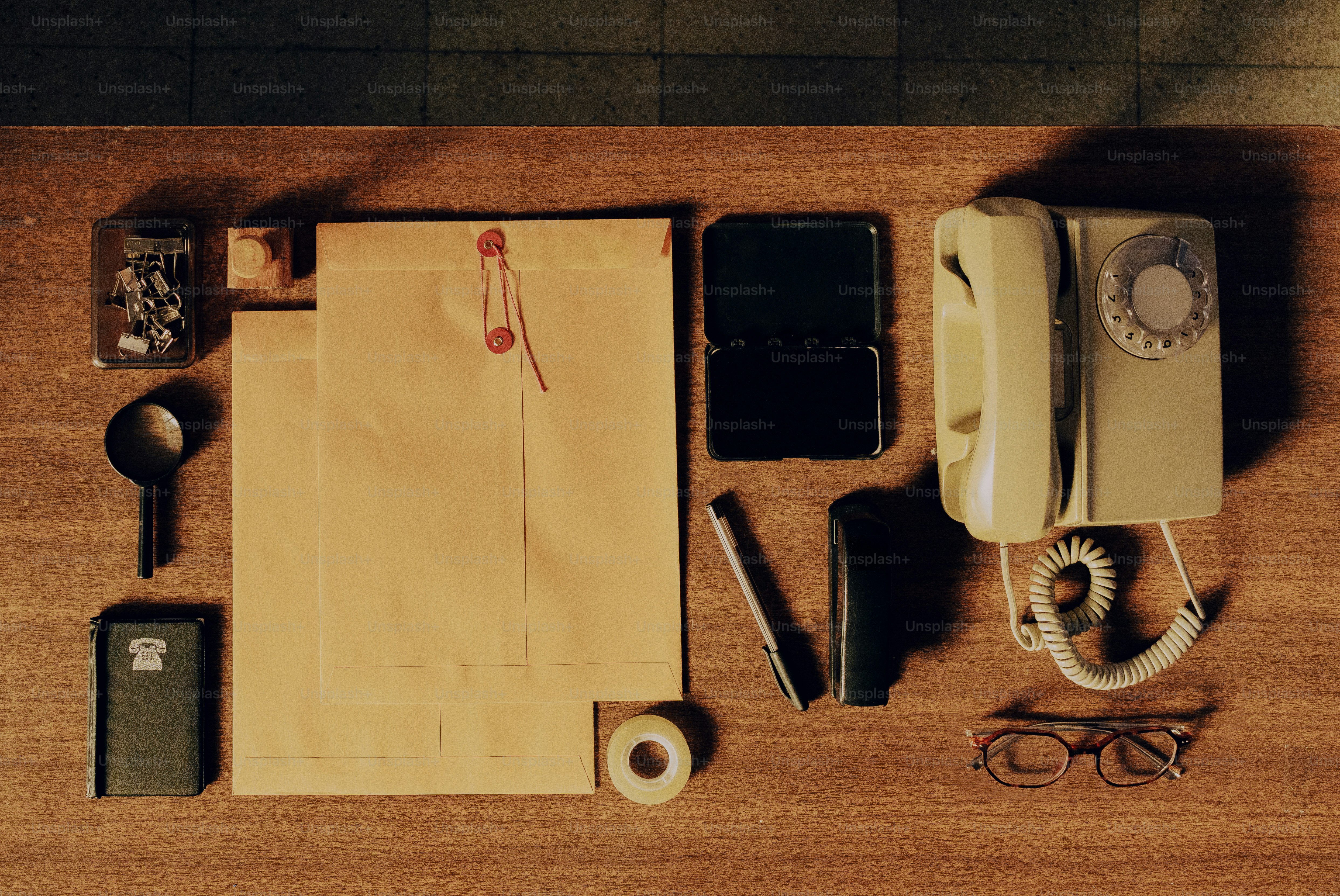 Desk with vintage phone, notepad, and stationery items.