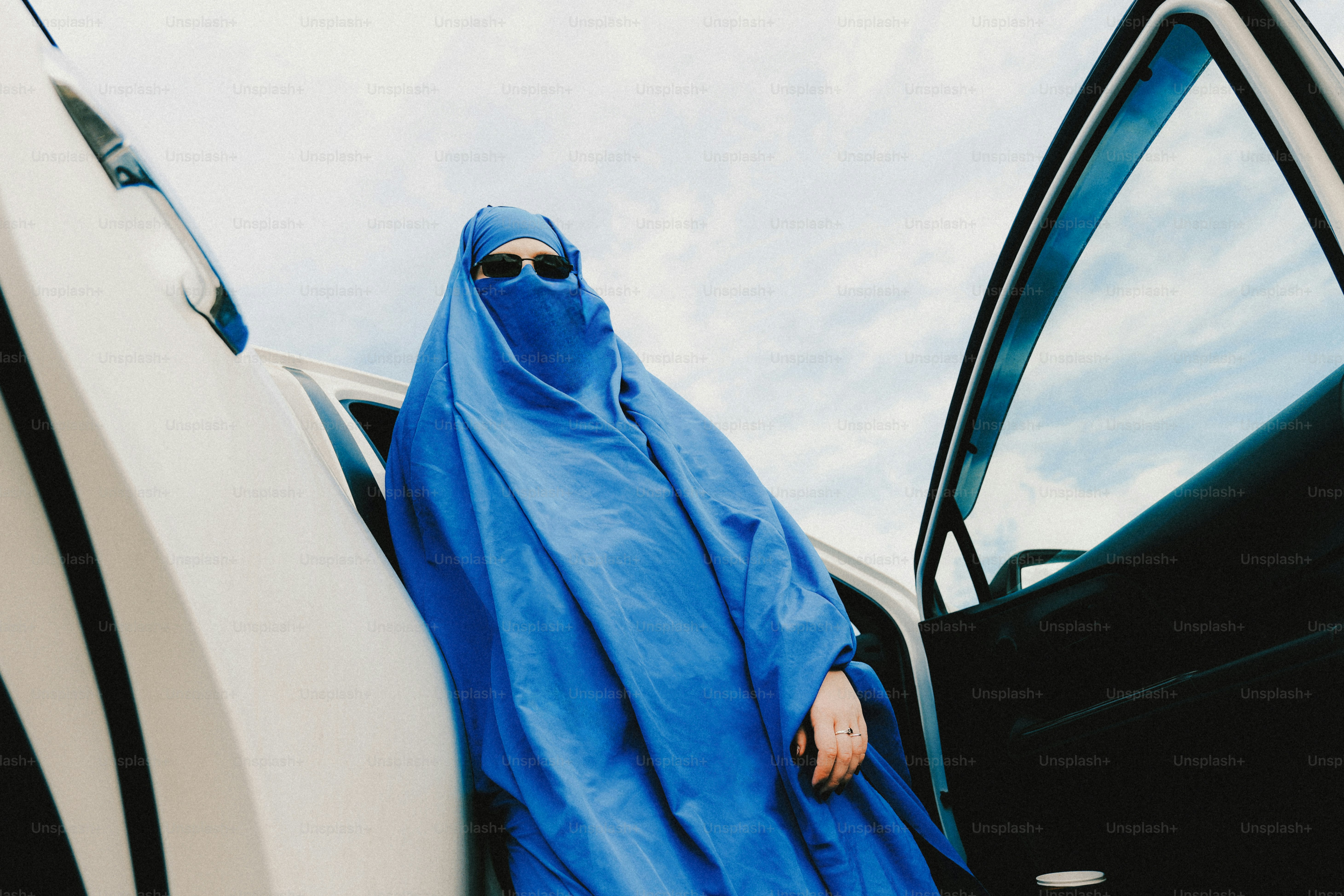 Wanita berburqa biru dan kacamata hitam dengan mobil