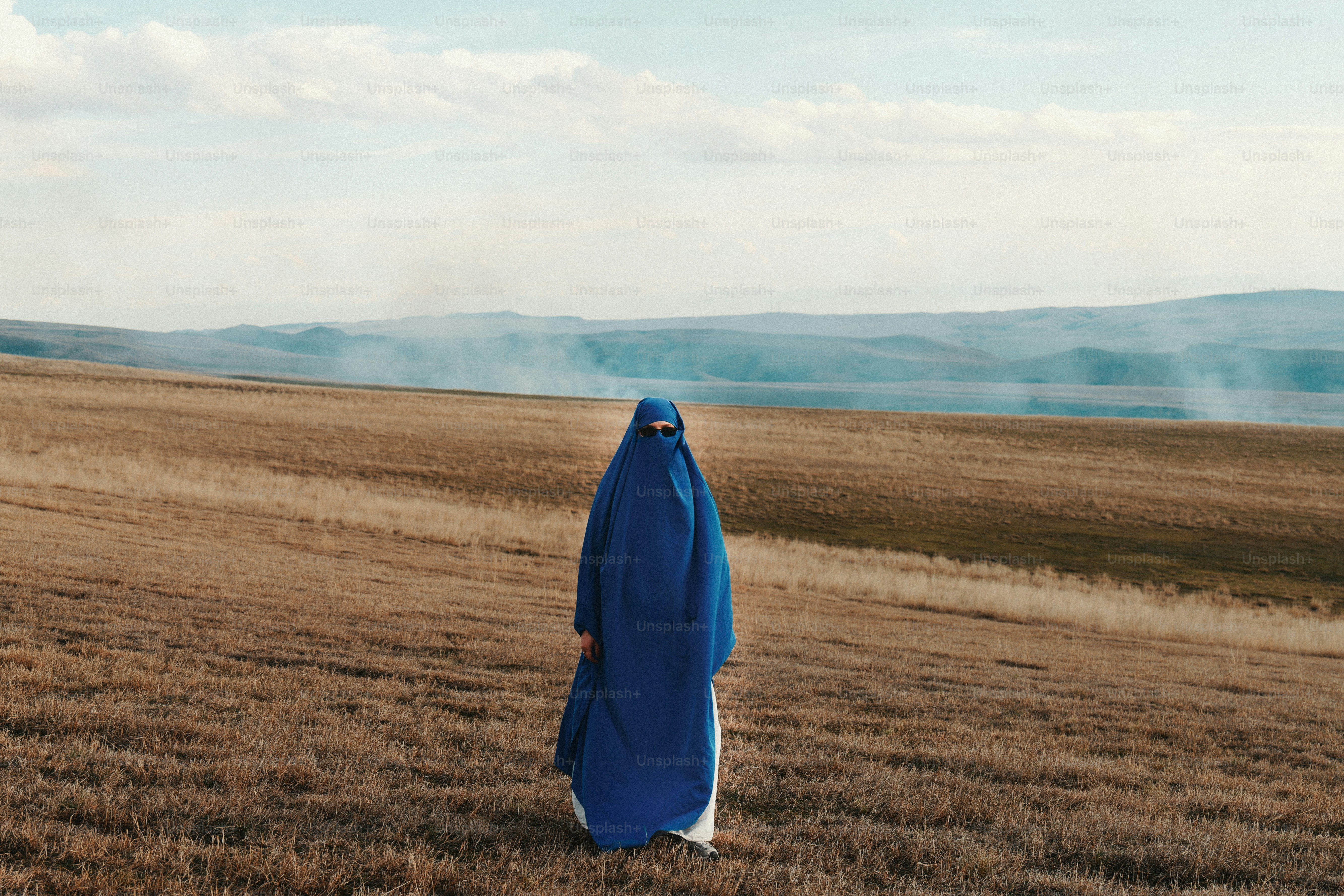 Wanita berburqa biru berdiri di ladang kering