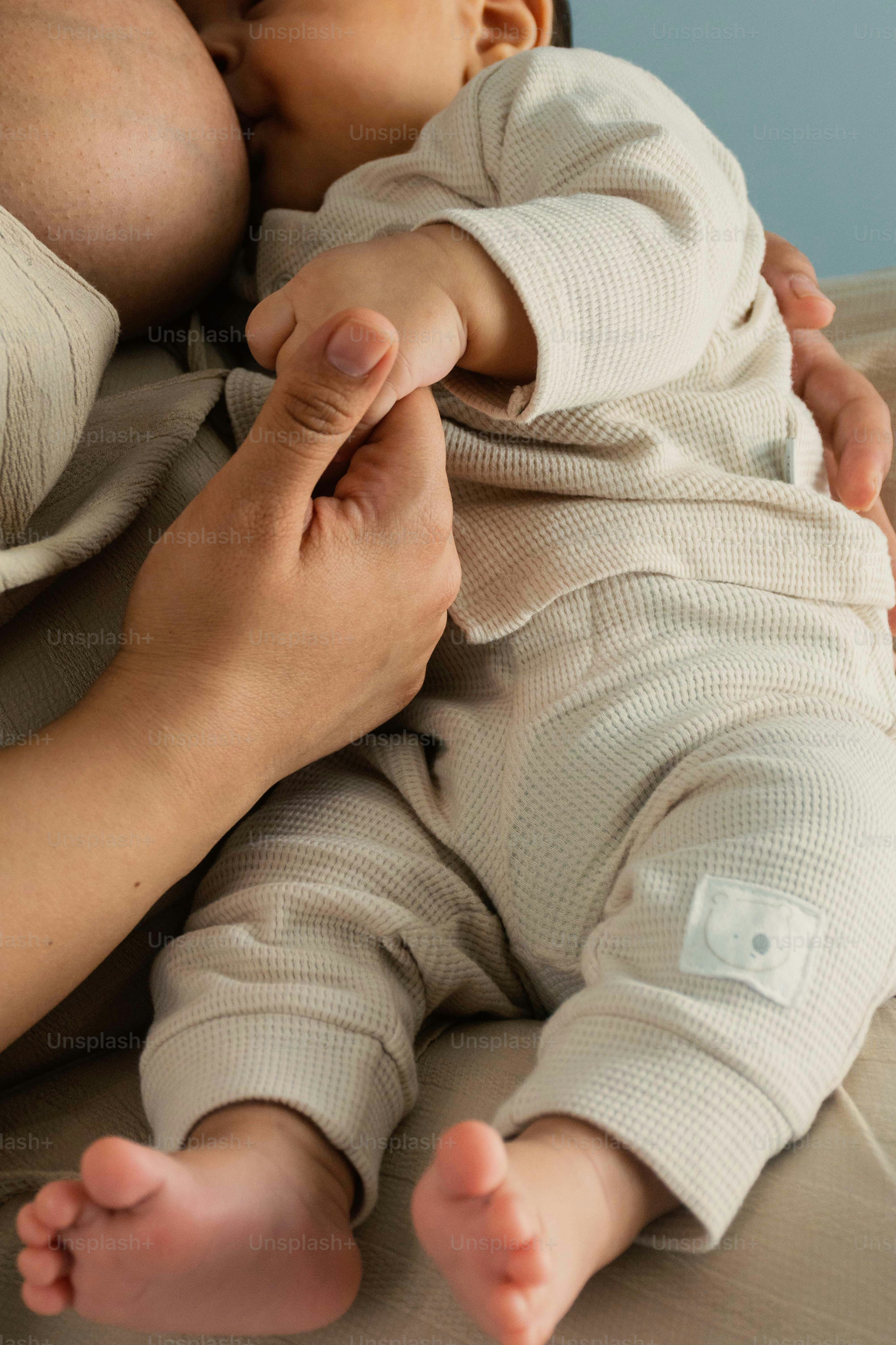 Madre che allatta il bambino con la mano del genitore che tiene la mano del bambino