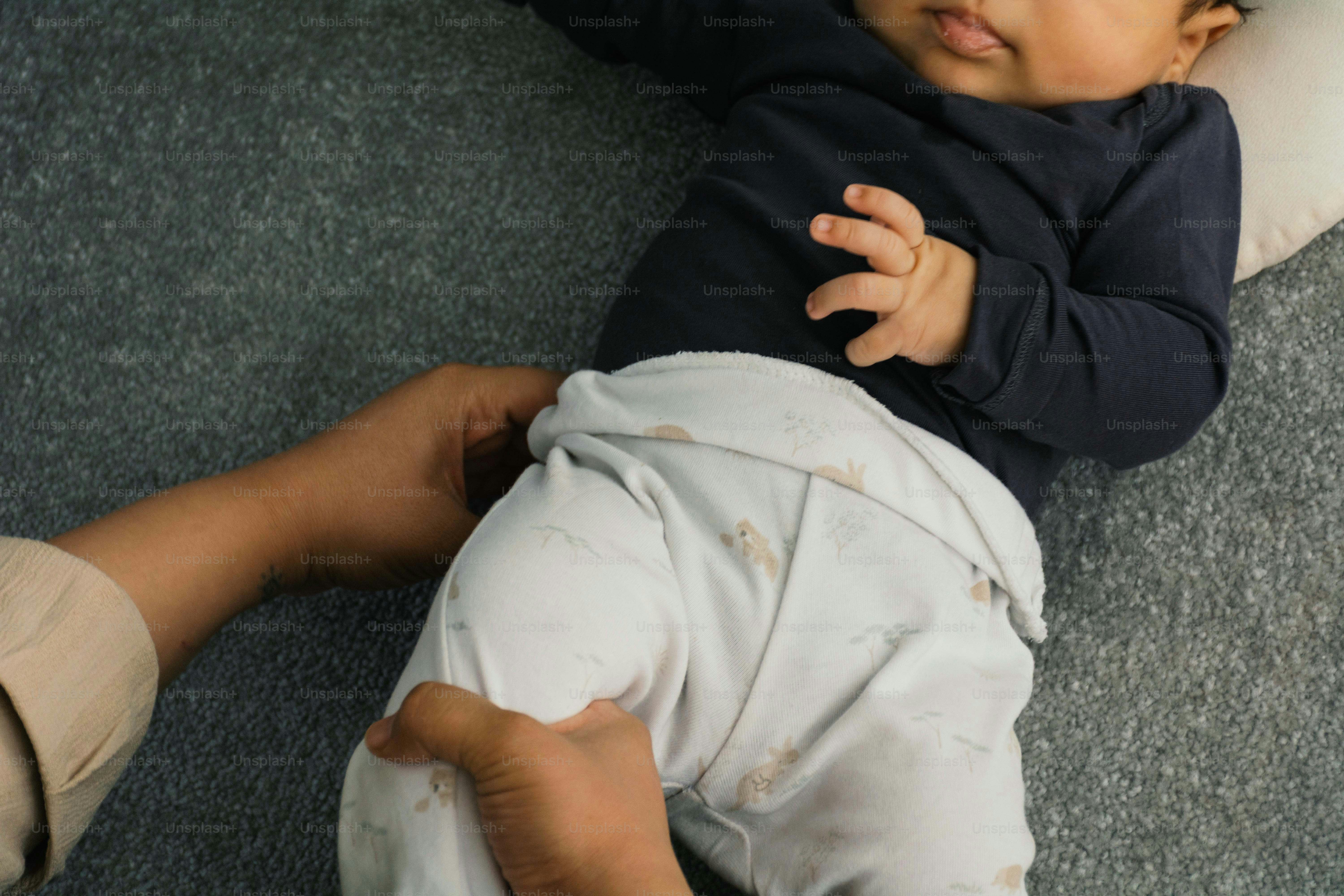 Il bambino sdraiato sulla schiena, tenuto in braccio da un adulto.