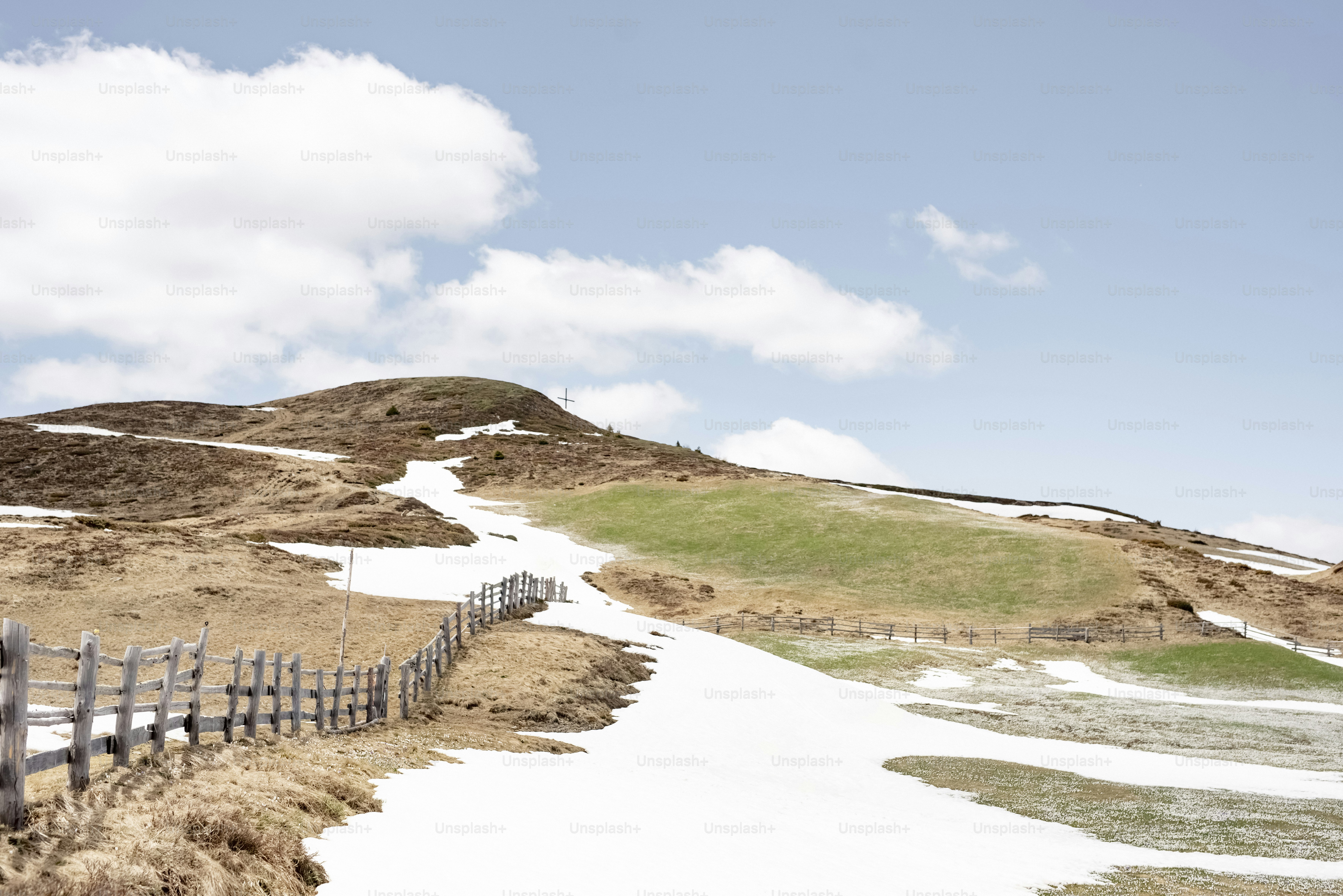 푸른 하늘 아래 나무 울타리가 있는 눈 덮인 언덕들