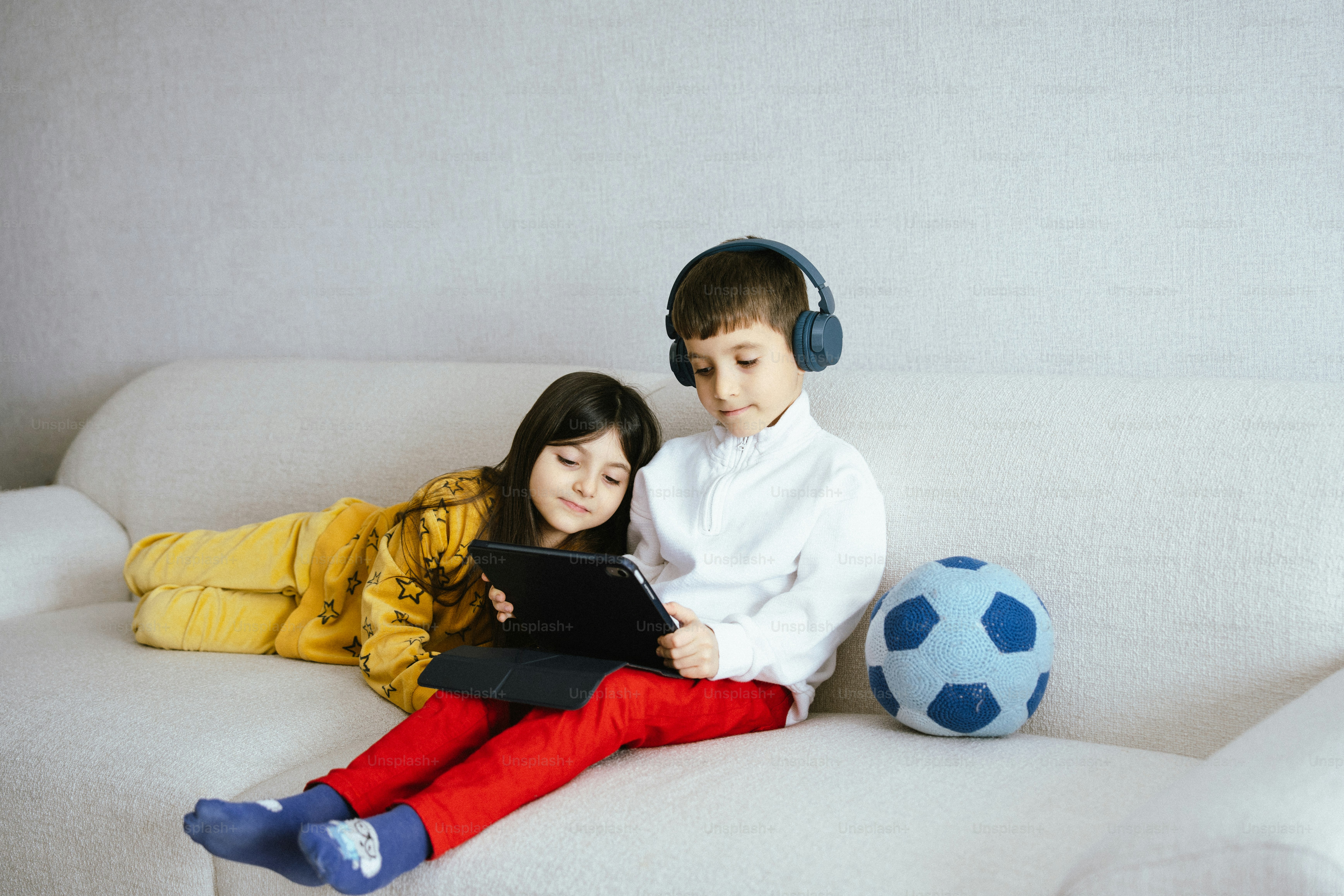Dos niños viendo una tablet en el sofá.
