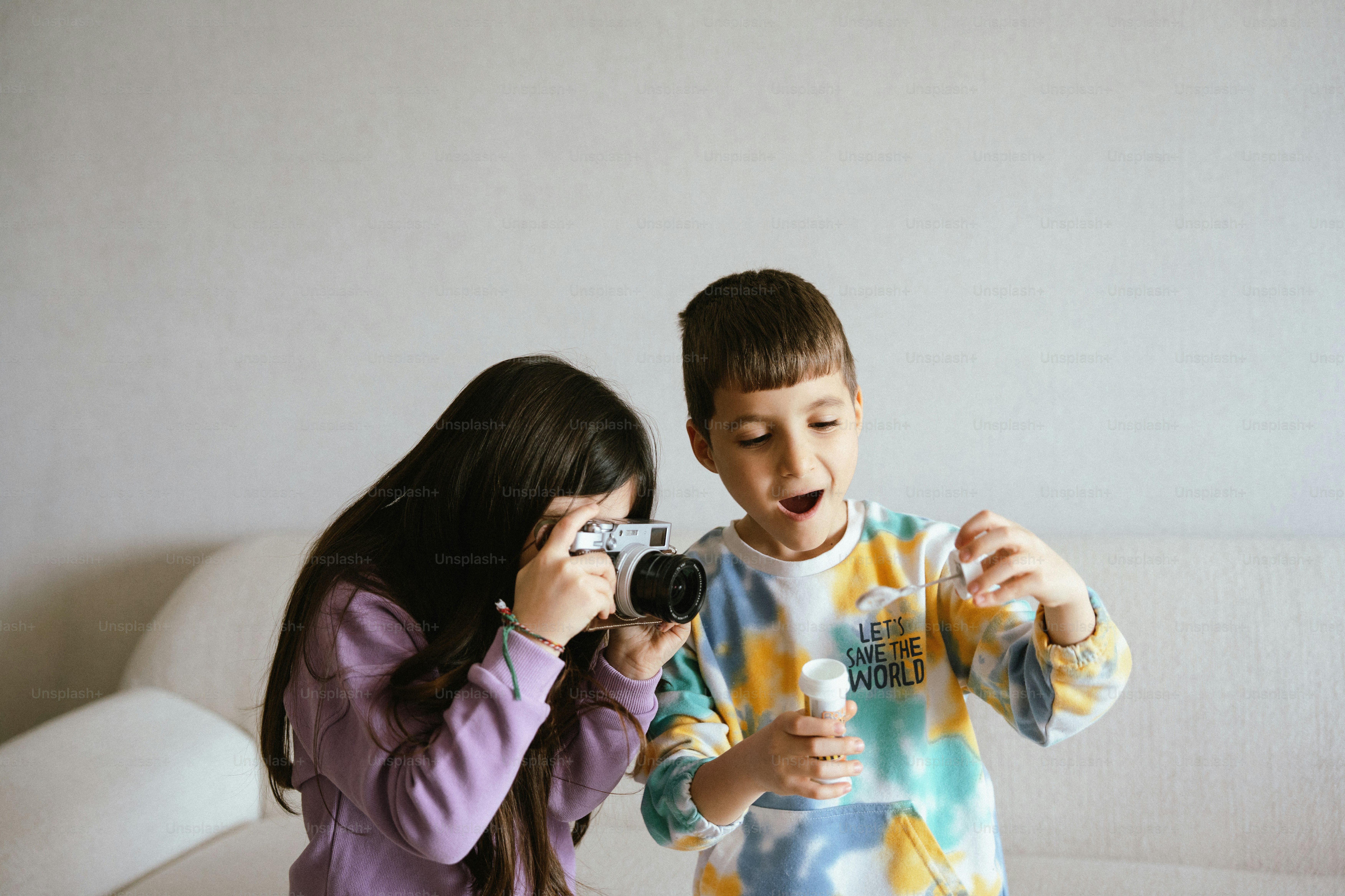 Chica saca foto a un chico soplando burbujas