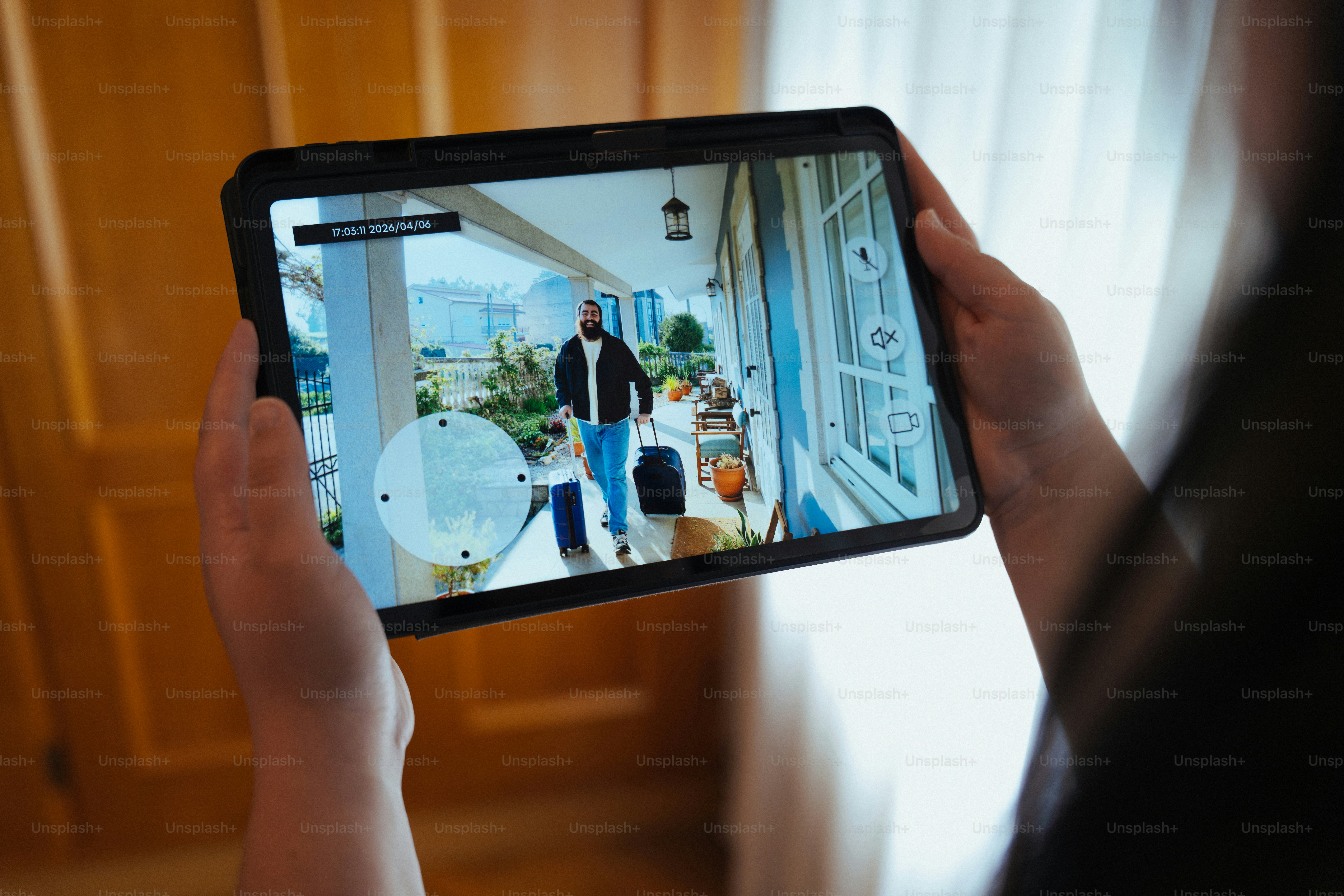 Person holding tablet showing security camera feed