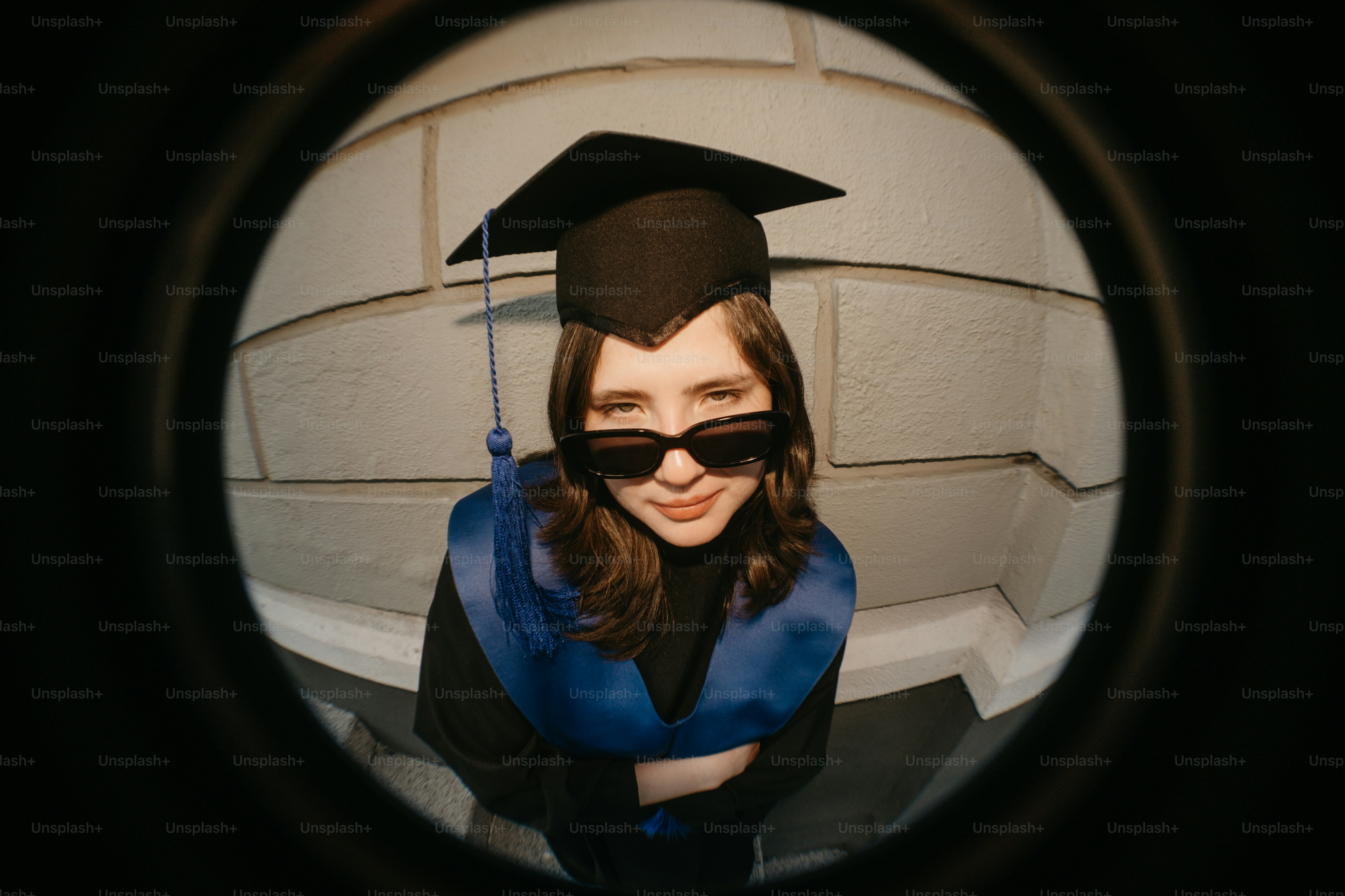 Un graduado con toga y gorra y gafas de sol