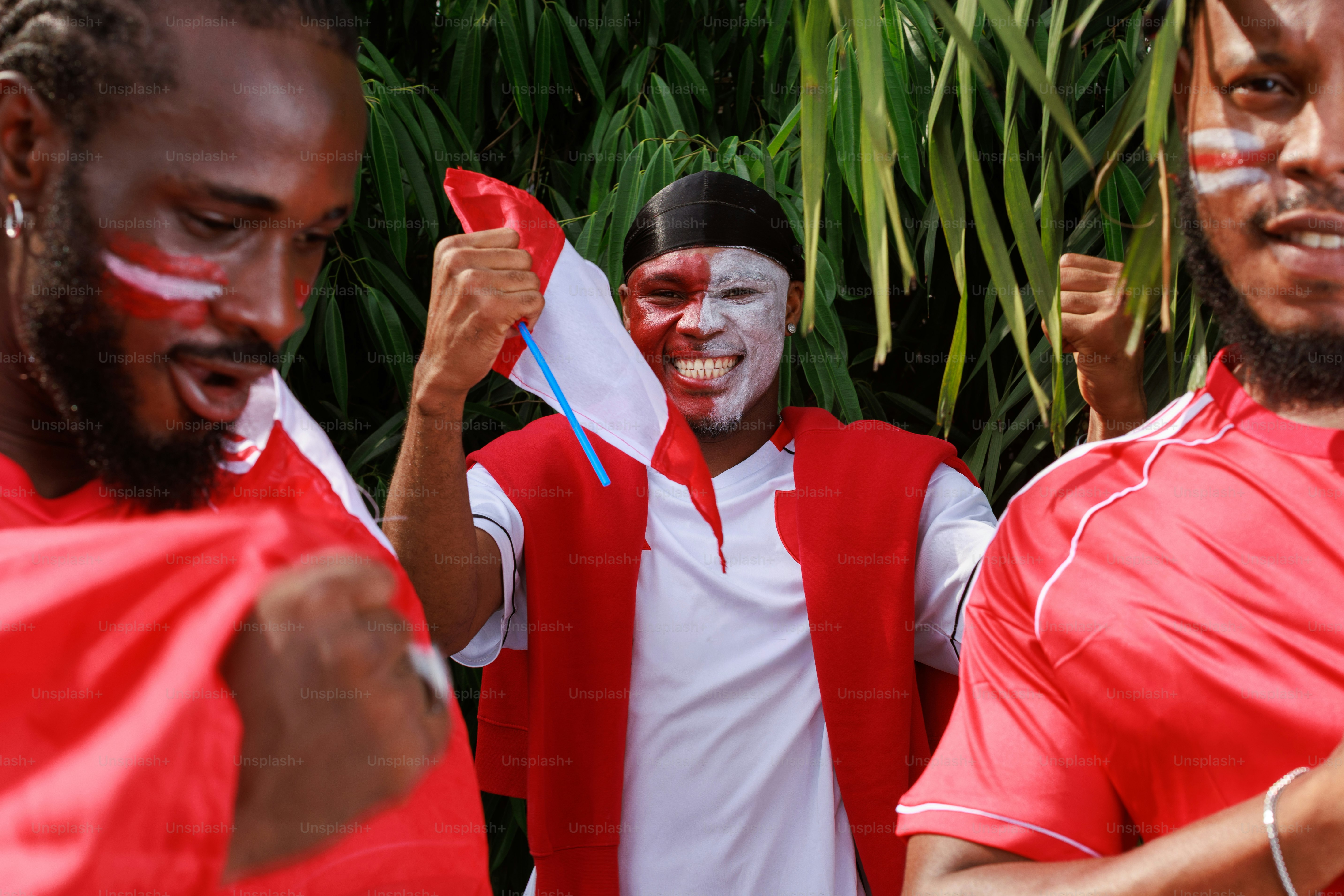 Tiga pria dengan wajah yang dicat dan pakaian merah dan putih