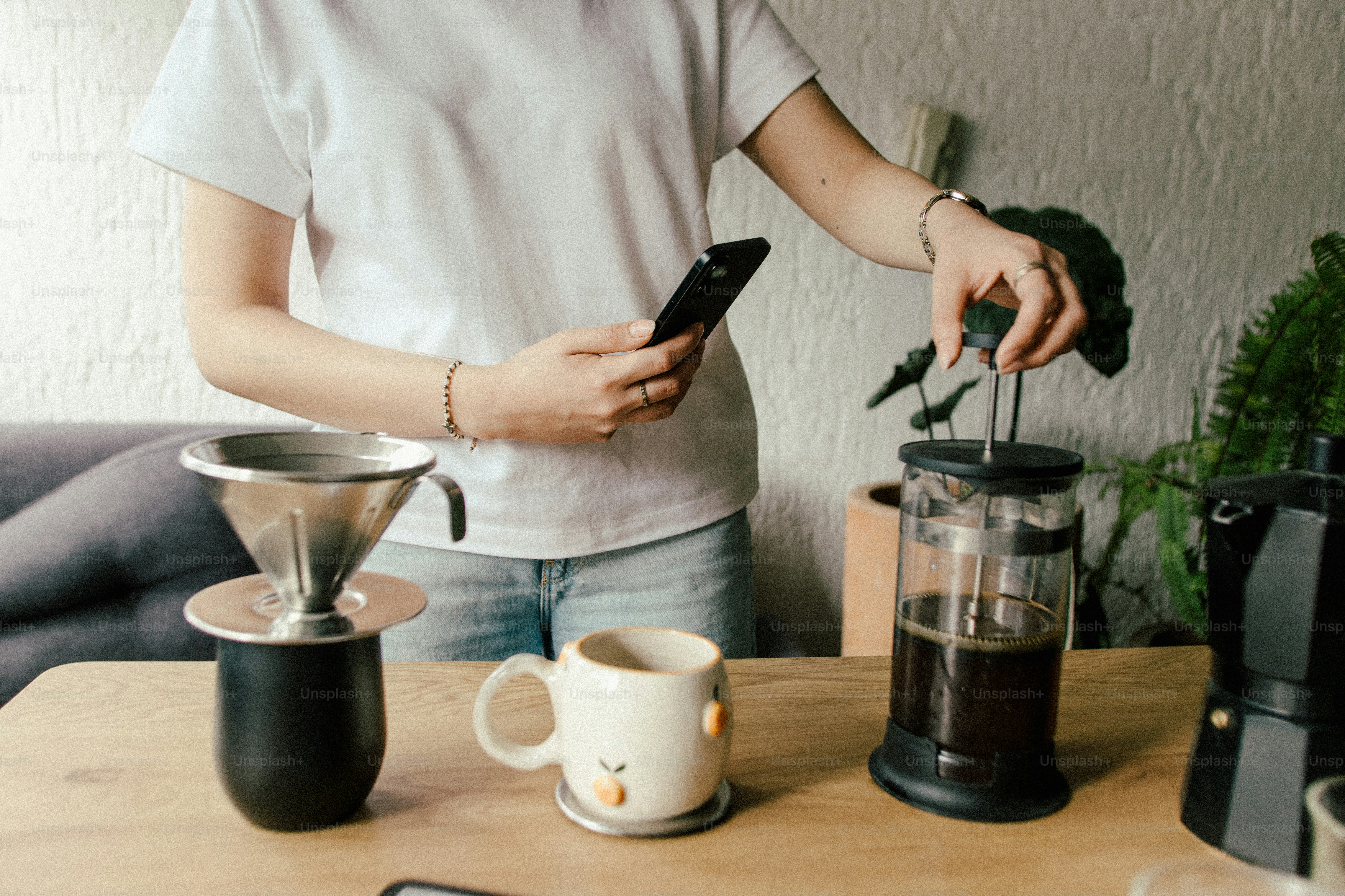 Femme qui prépare du café avec une presse française et un pour-over.