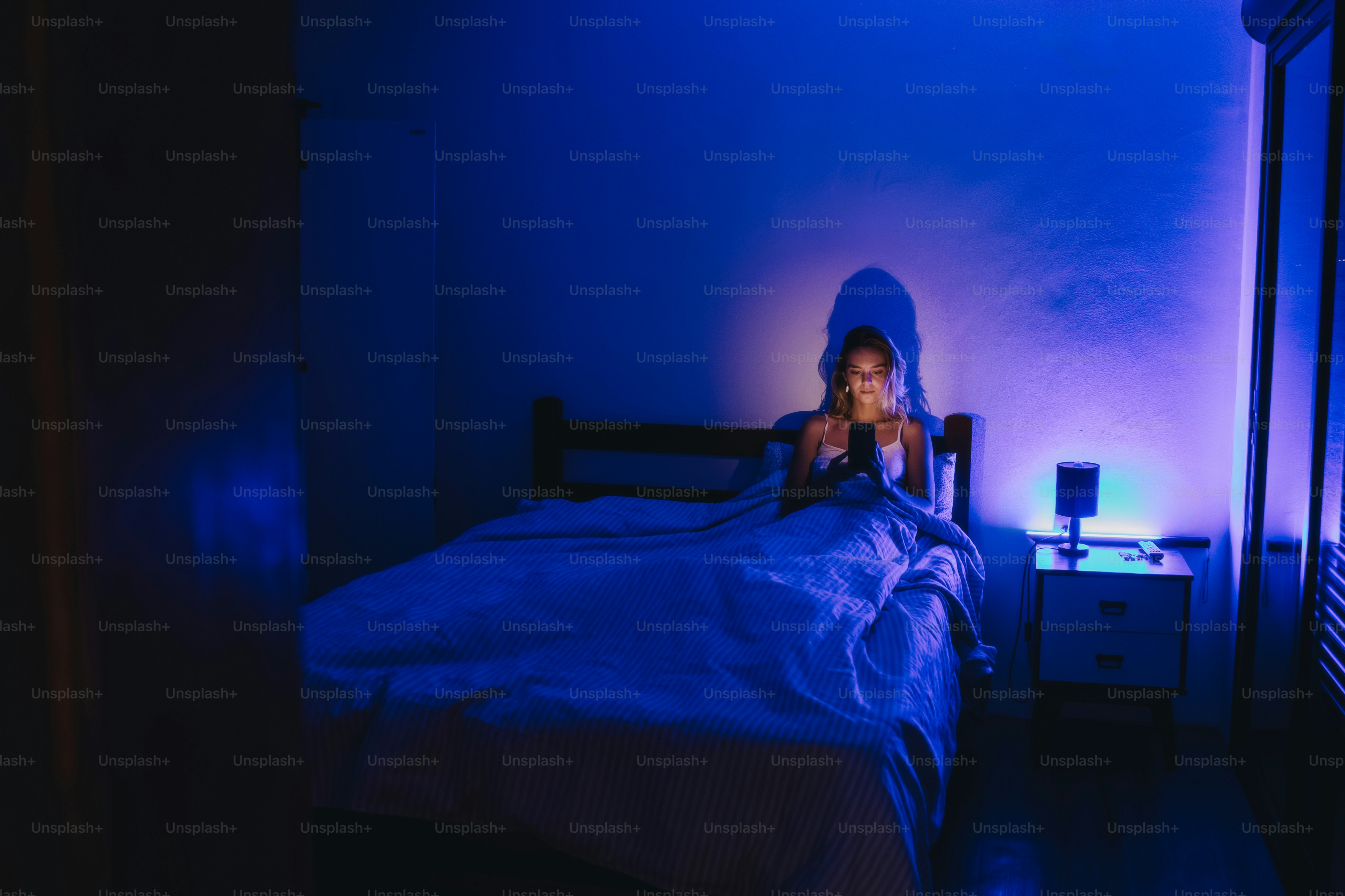 Mujer usando el móvil en la cama por la noche