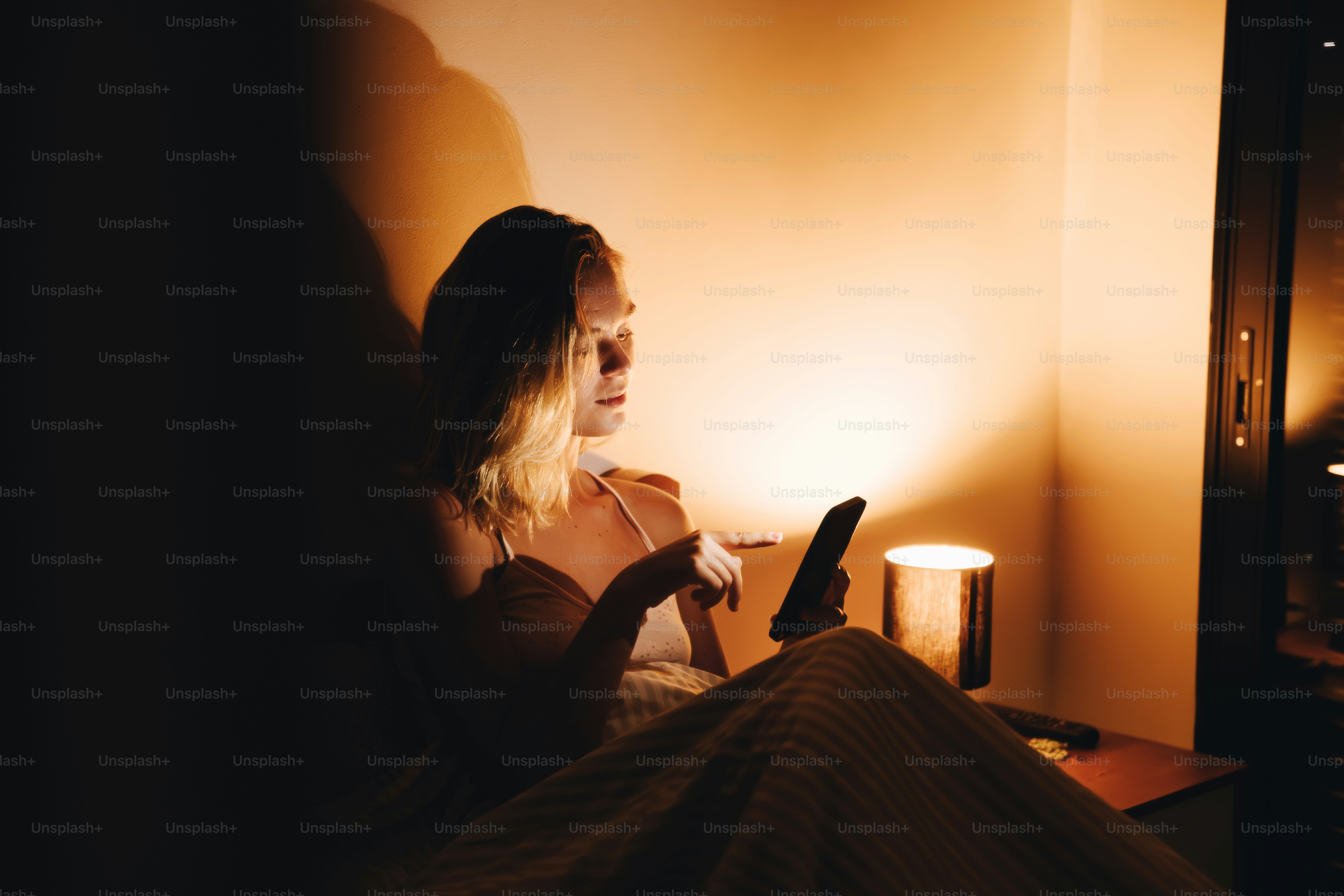 Mujer usando el teléfono en una habitación tenuemente iluminada