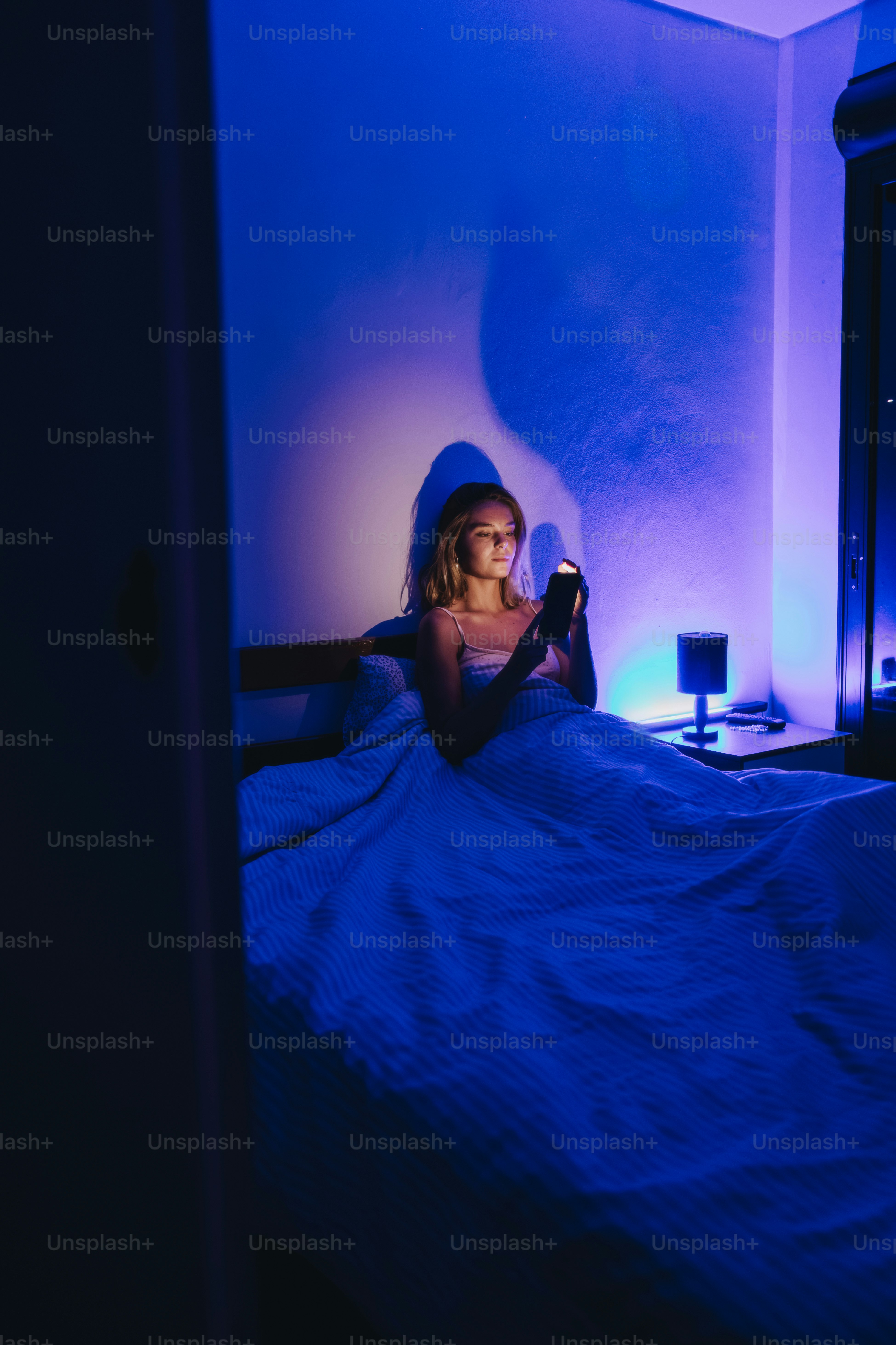 Mujer usando el teléfono en la cama con luz azul