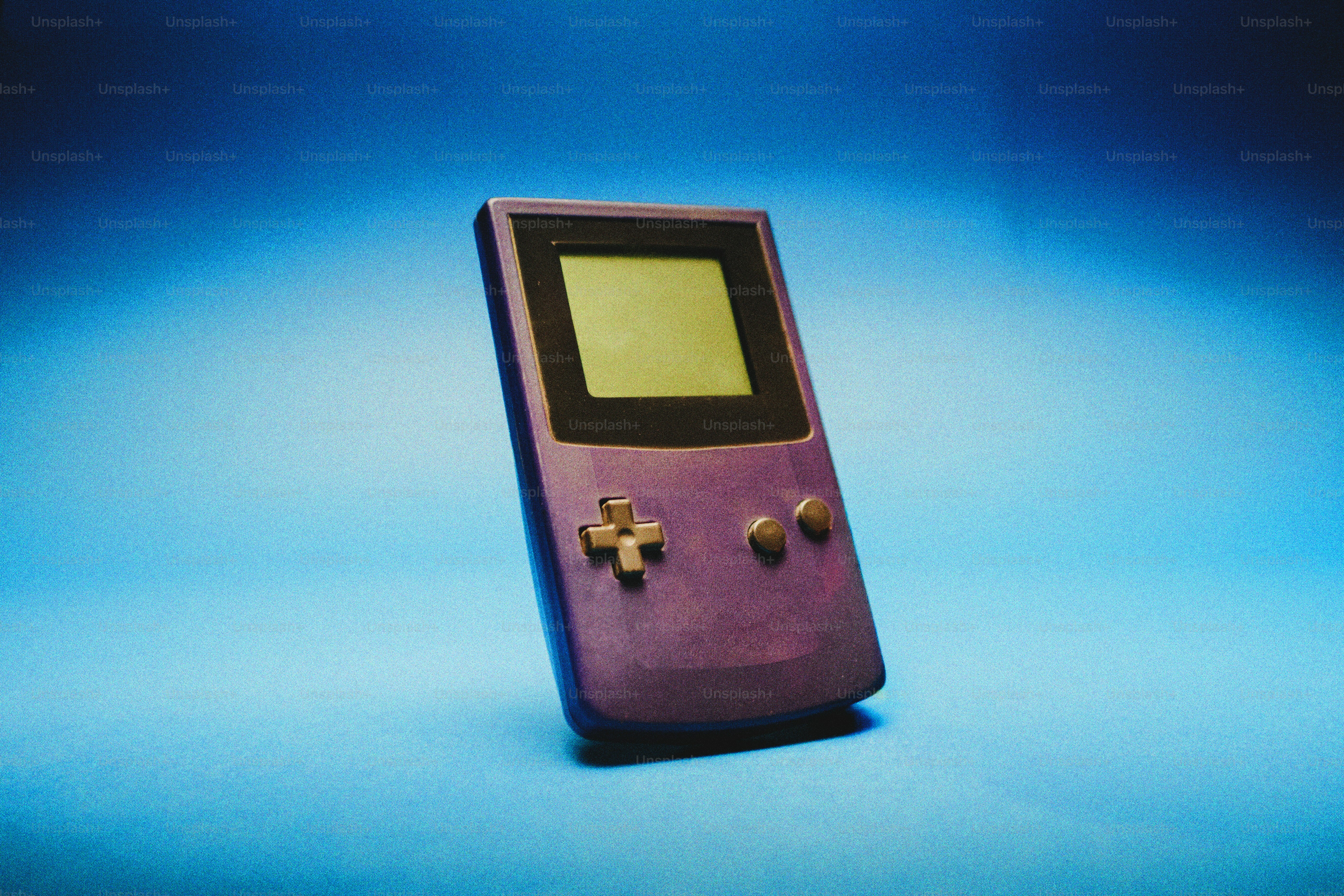 Un Game Boy violet repose sur un fond bleu.