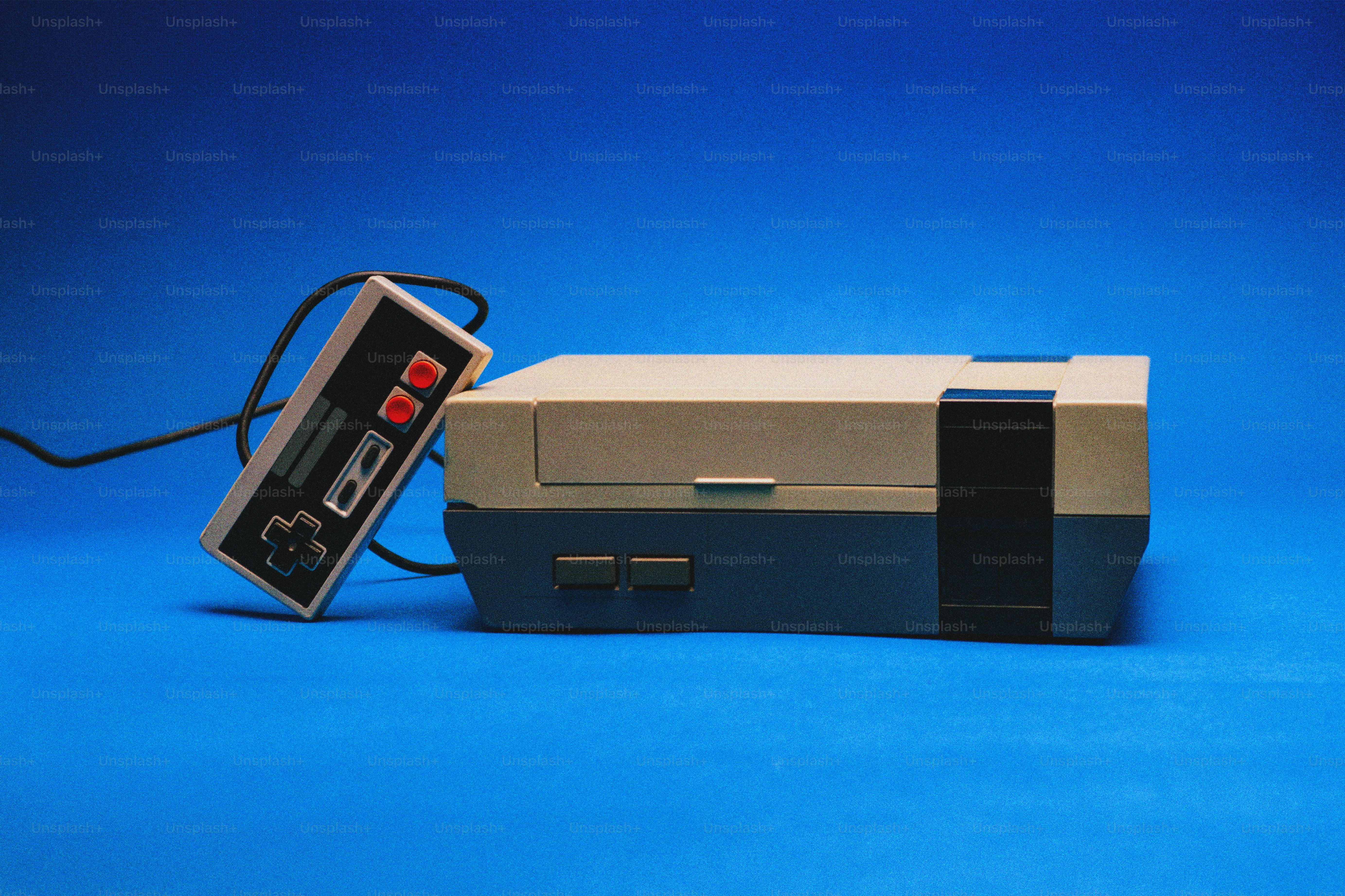 Console de jeux vidéo vintage et manette sur fond bleu