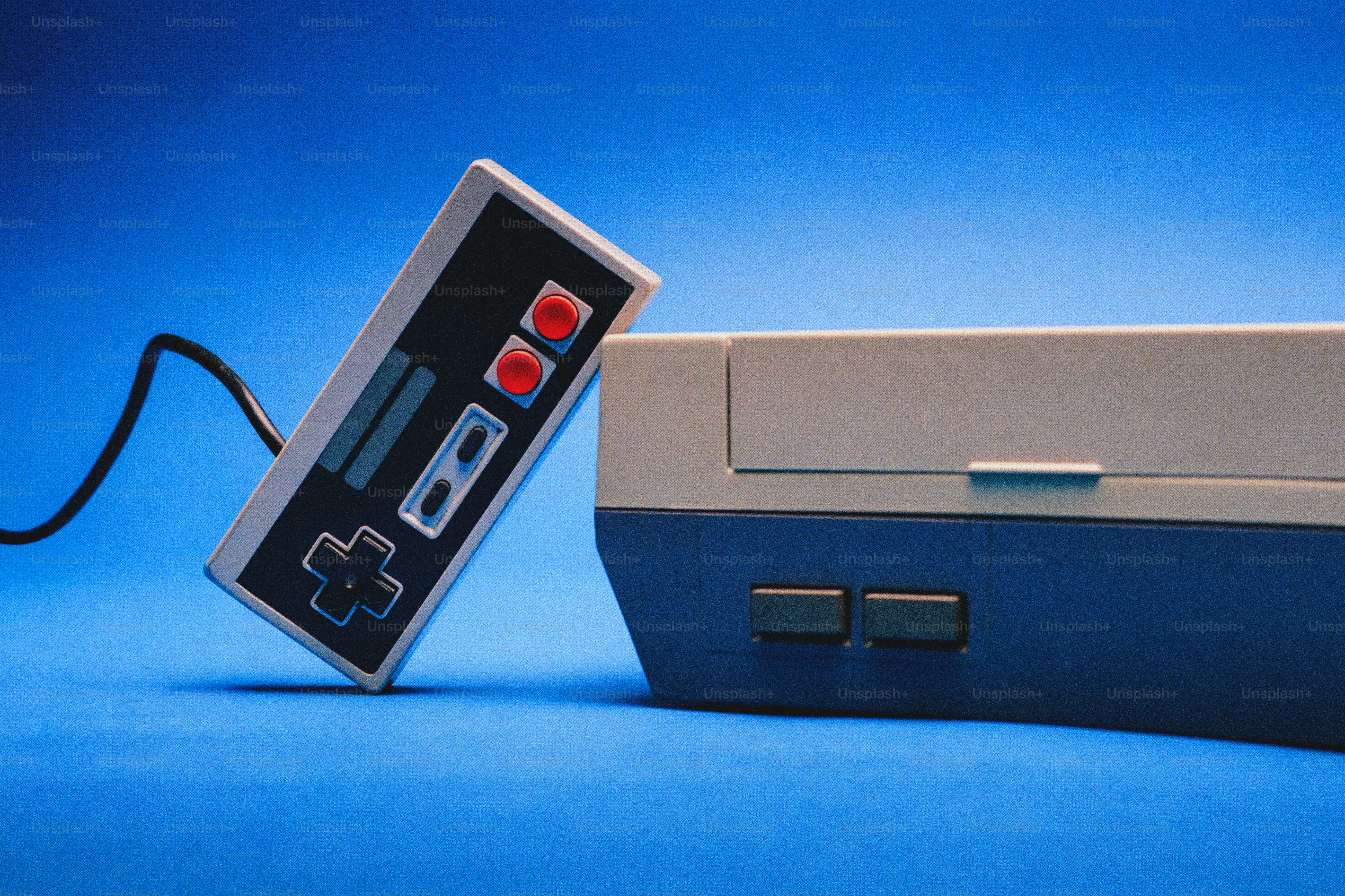 Console de jeux vidéo vintage et manette sur fond bleu