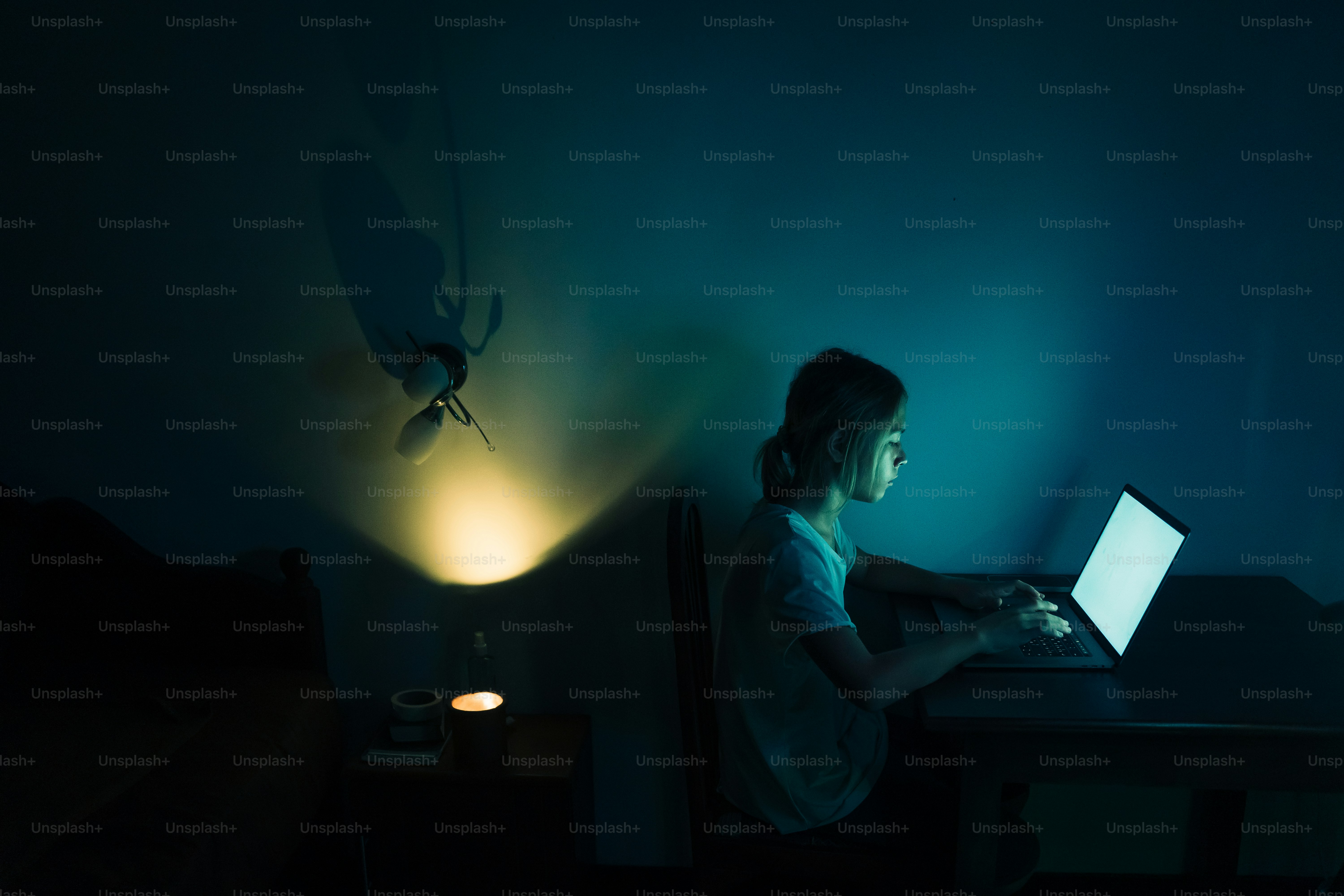 Orang yang bekerja di laptop di ruangan yang remang-remang.
