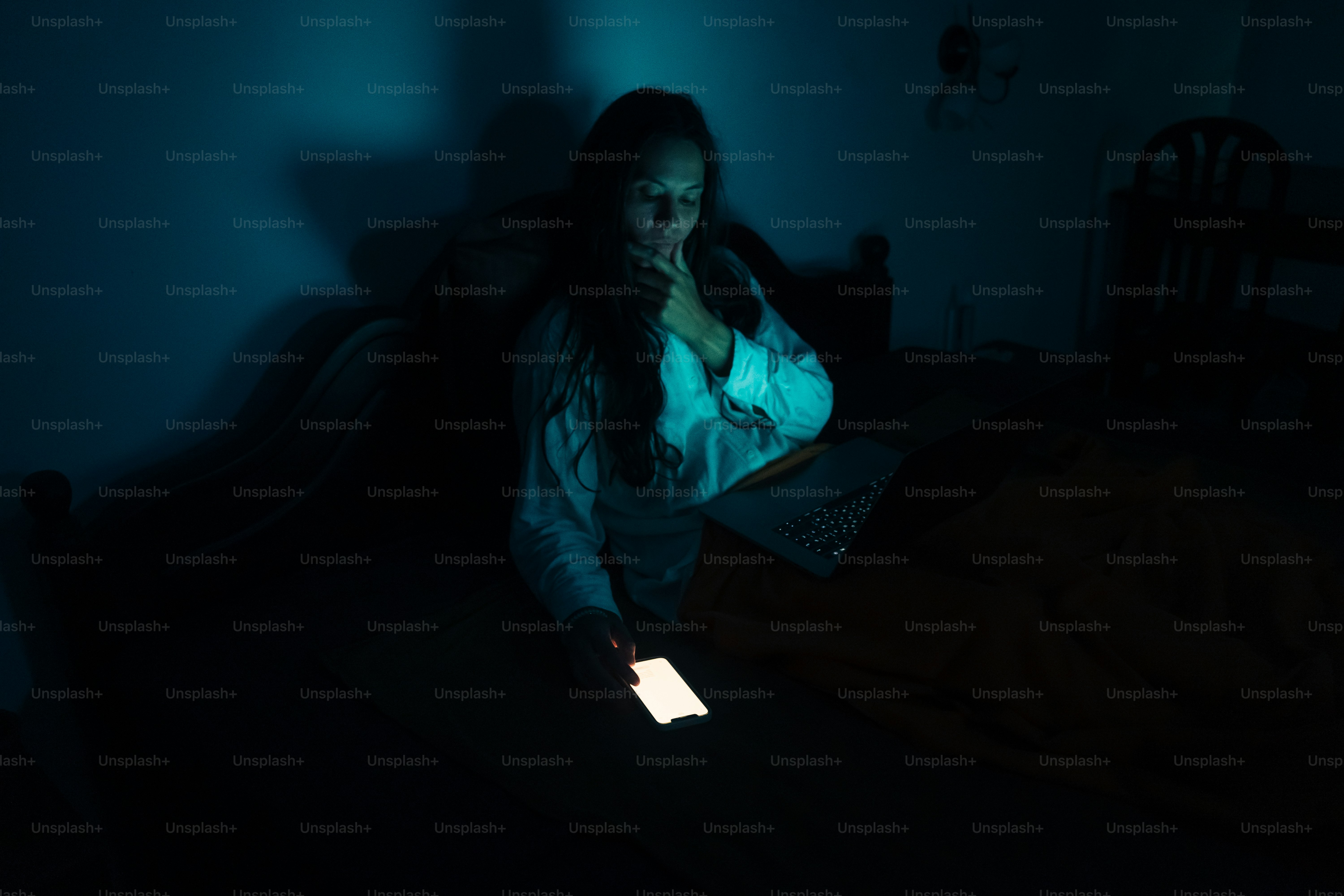 Woman in bed illuminated by phone screen