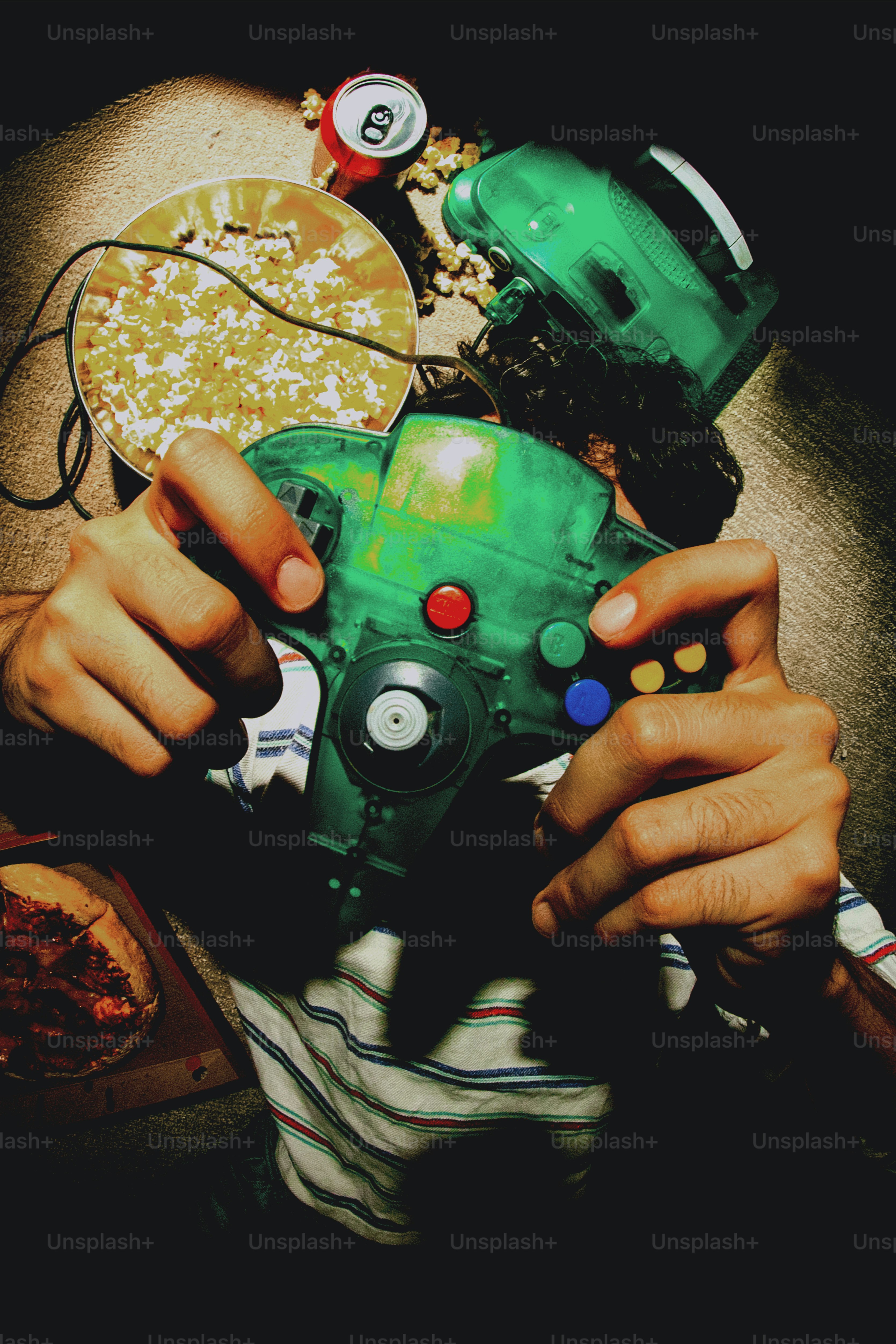 Les mains tenant une manette de jeu vidéo avec une pizza et des snacks.