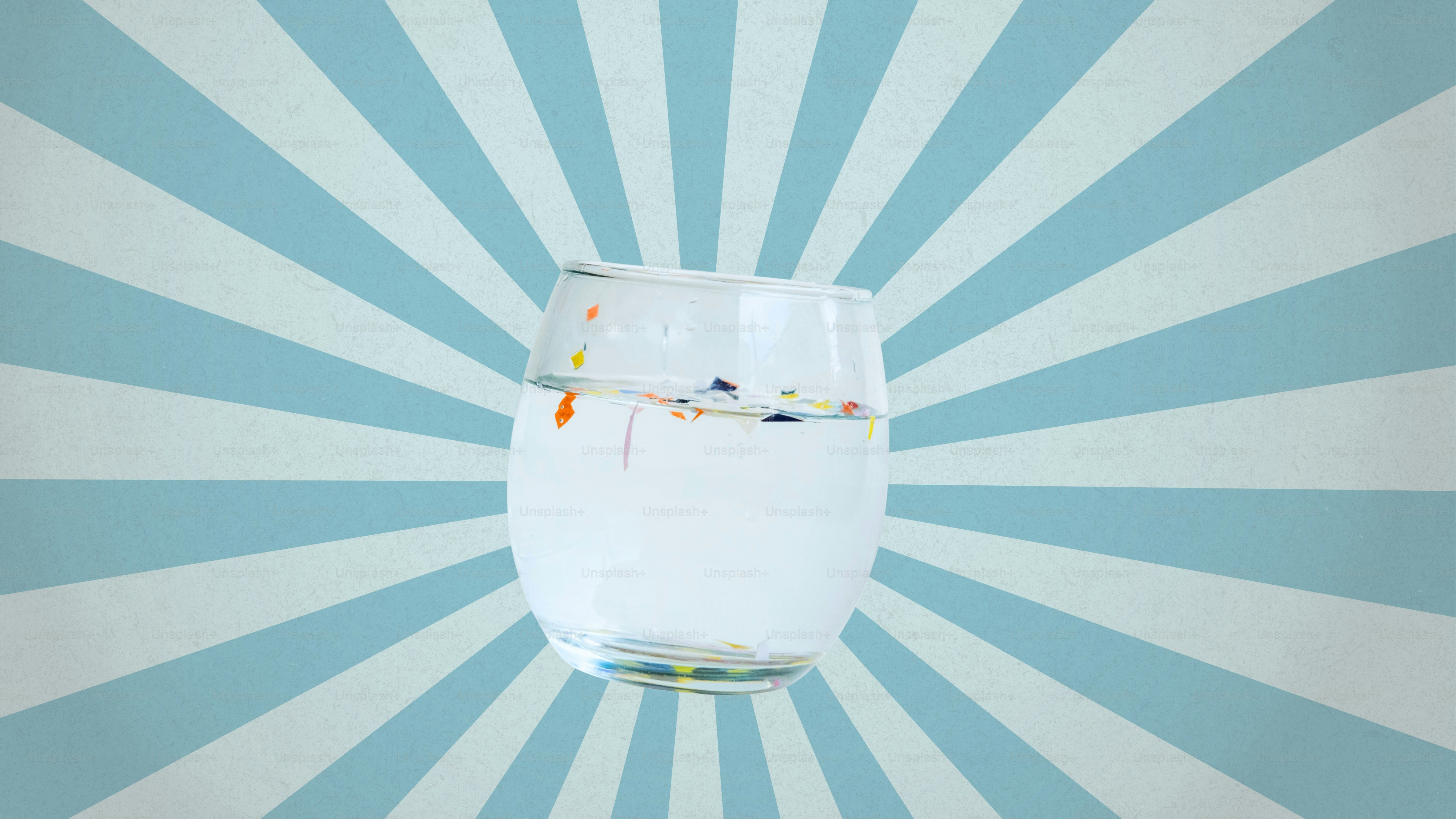 Glas Wasser mit bunten Gegenständen, die darin schwimmen