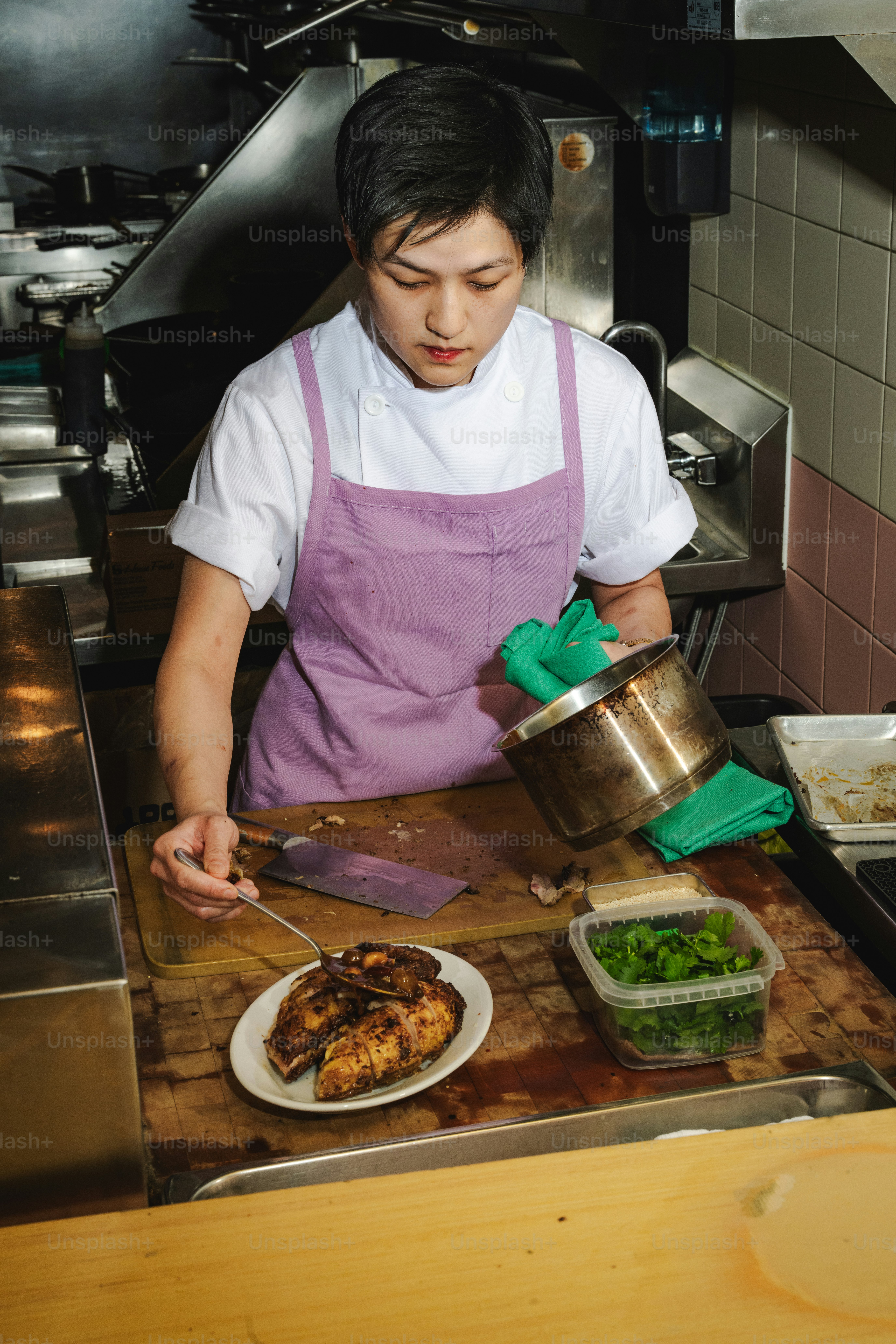 A chef plates seasoned chicken in a professional kitchen.