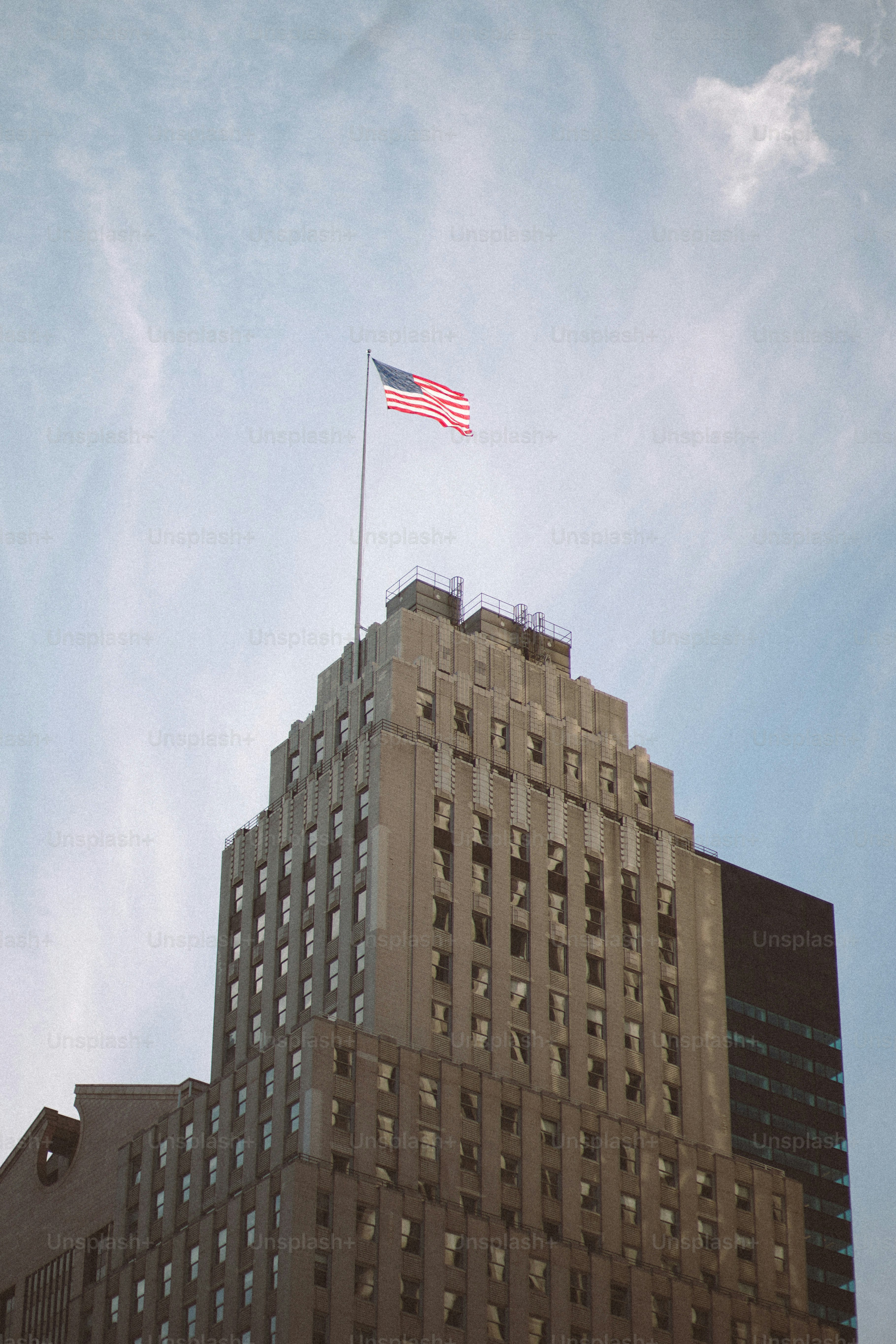 Drapeau américain au sommet d’un grand bâtiment sous un ciel nuageux