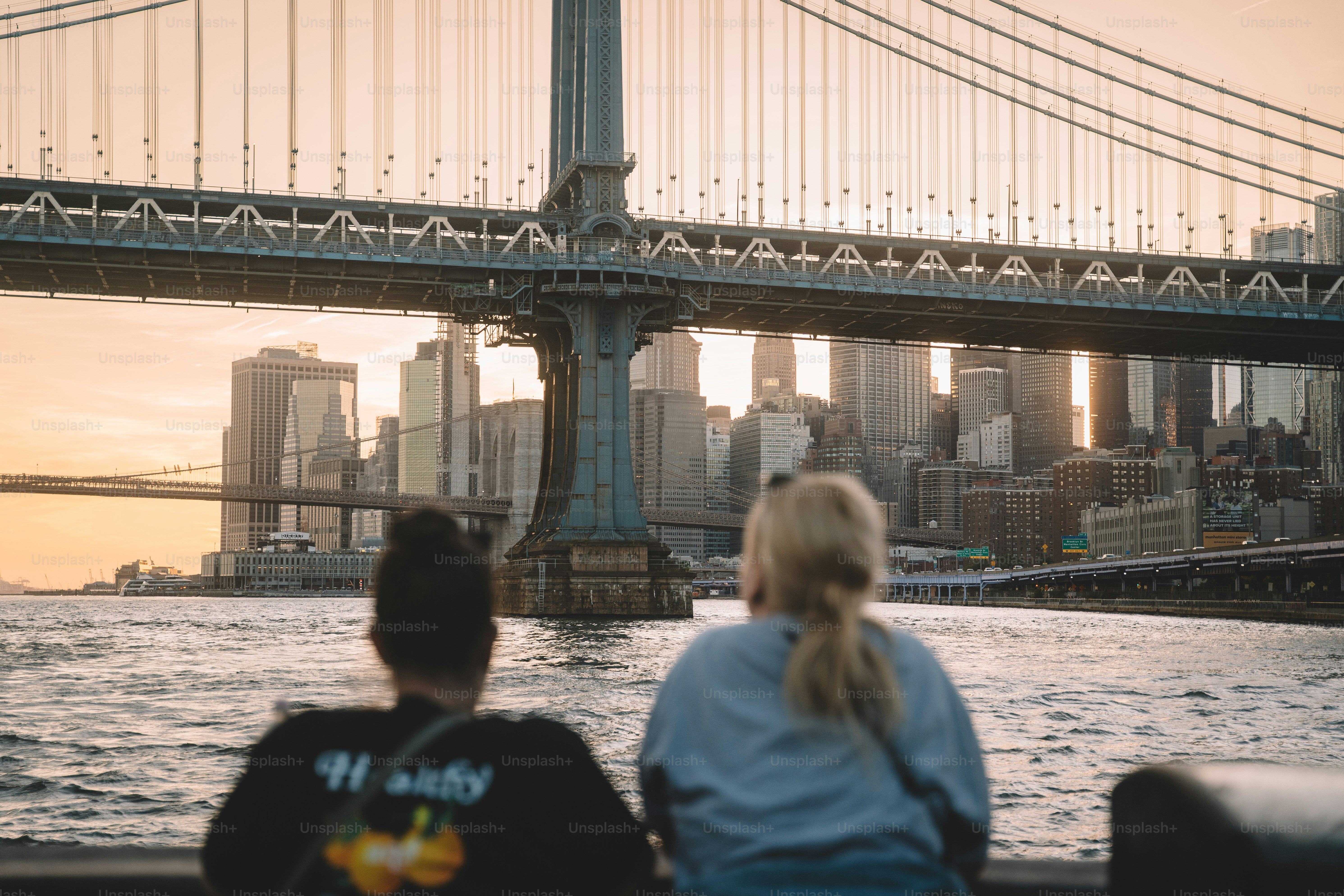 Dua orang menyaksikan matahari terbenam di atas pemandangan kota.