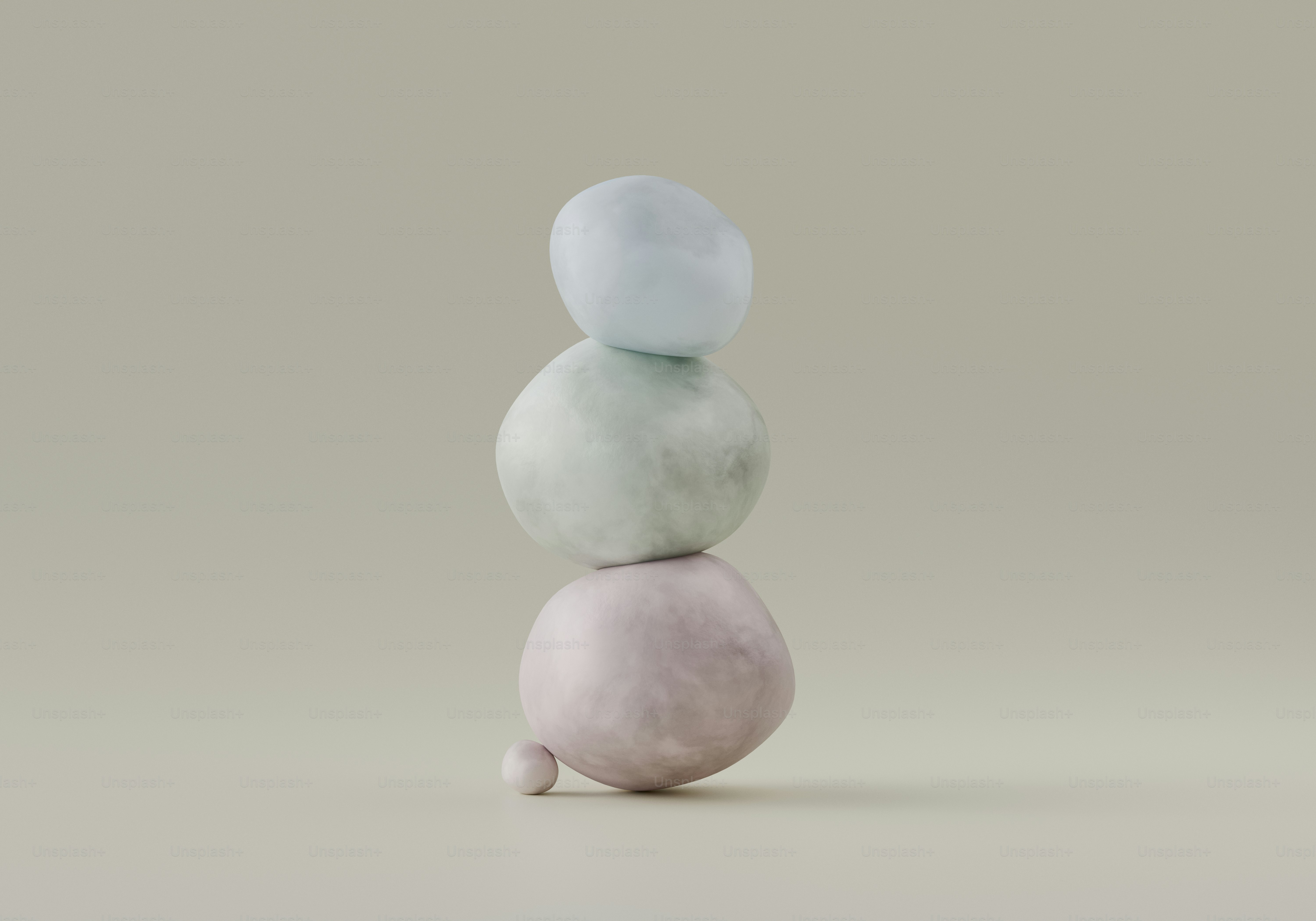 Three pastel colored stones stacked on a neutral background.