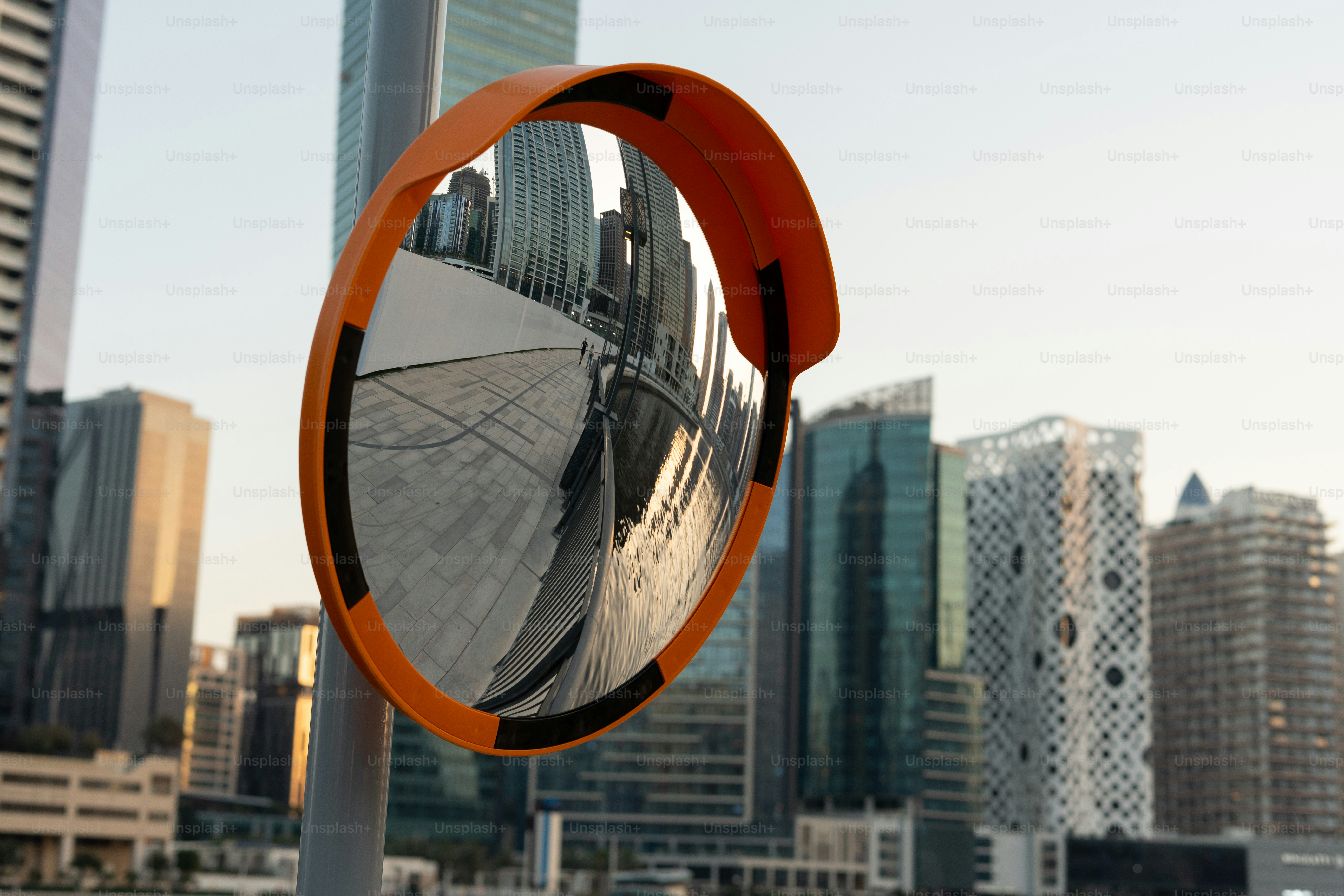 Konvexer Spiegel, der moderne Stadtgebäude und Himmel reflektiert.