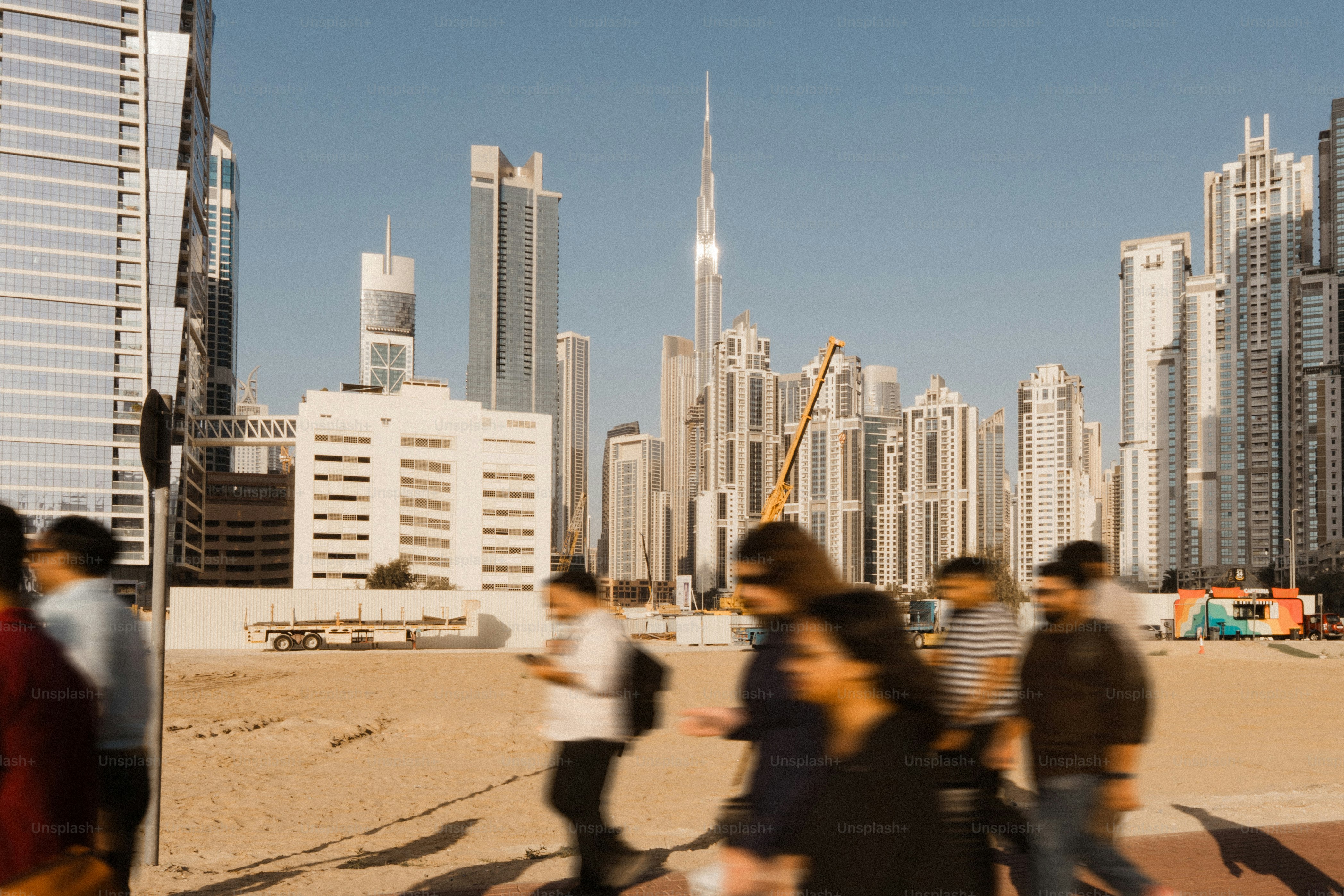 Die Menschen gehen an modernen Wolkenkratzern unter klarem blauen Himmel vorbei.