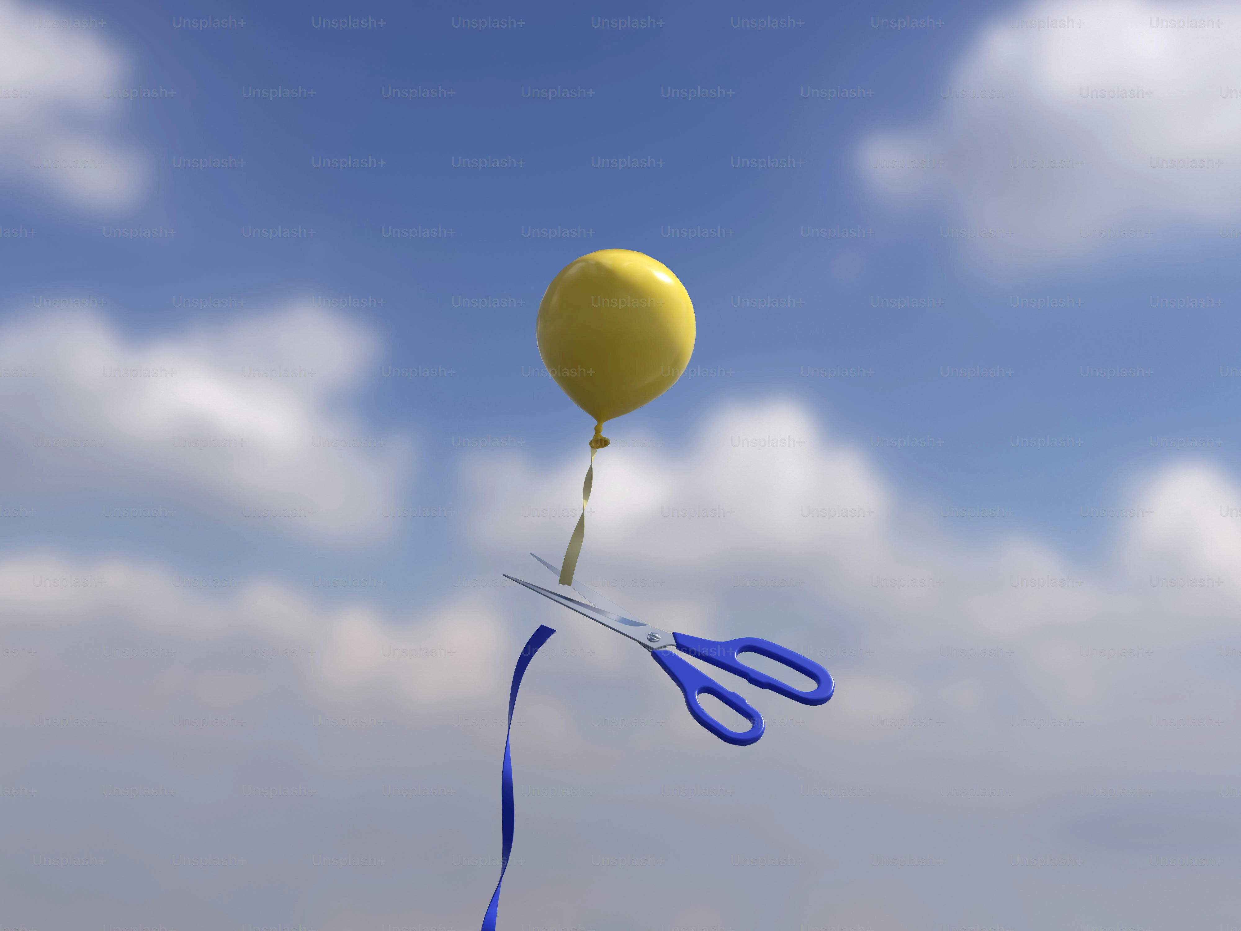Un ballon jaune avec des ciseaux coupant sa ficelle