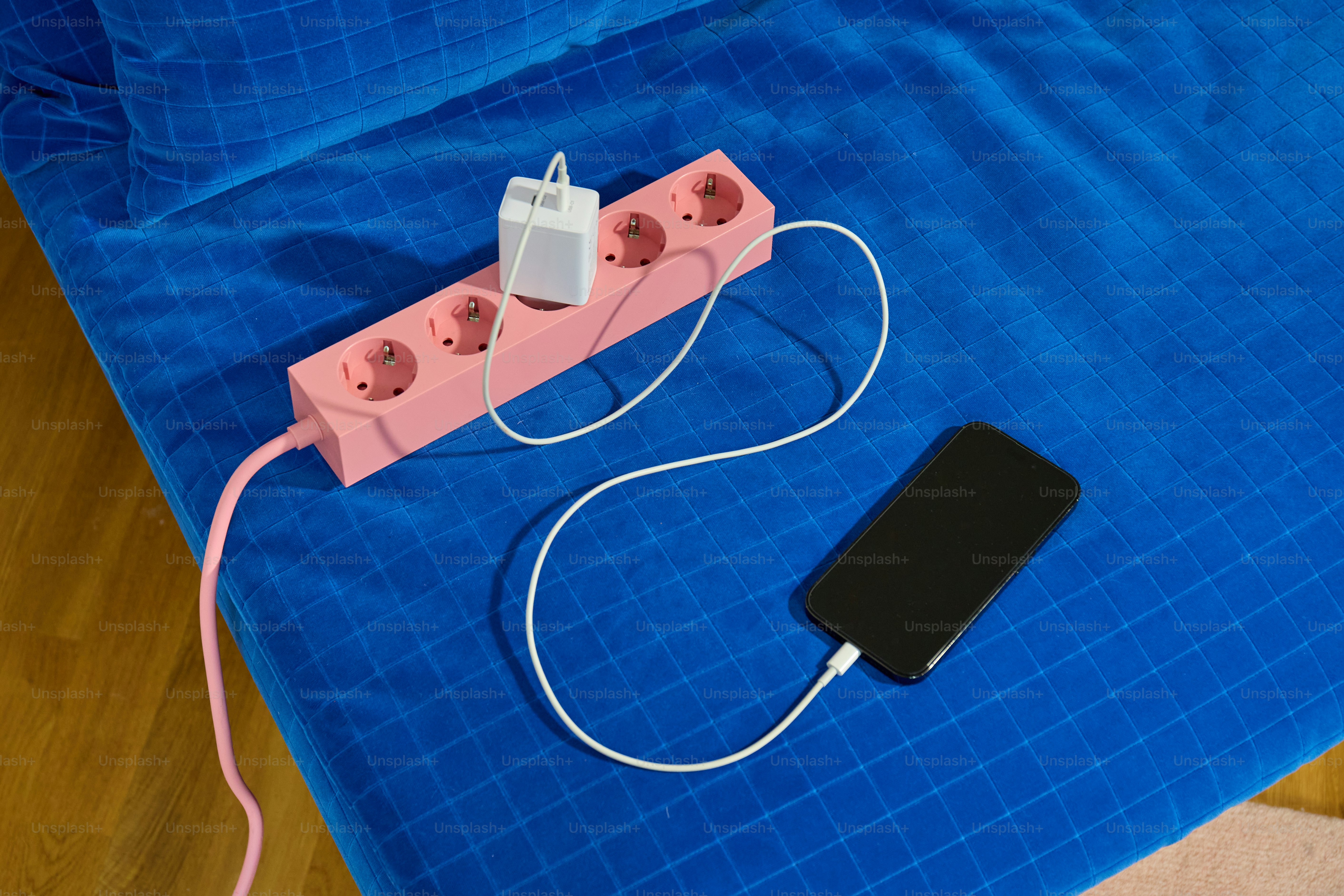 A pink power strip with a phone charging
