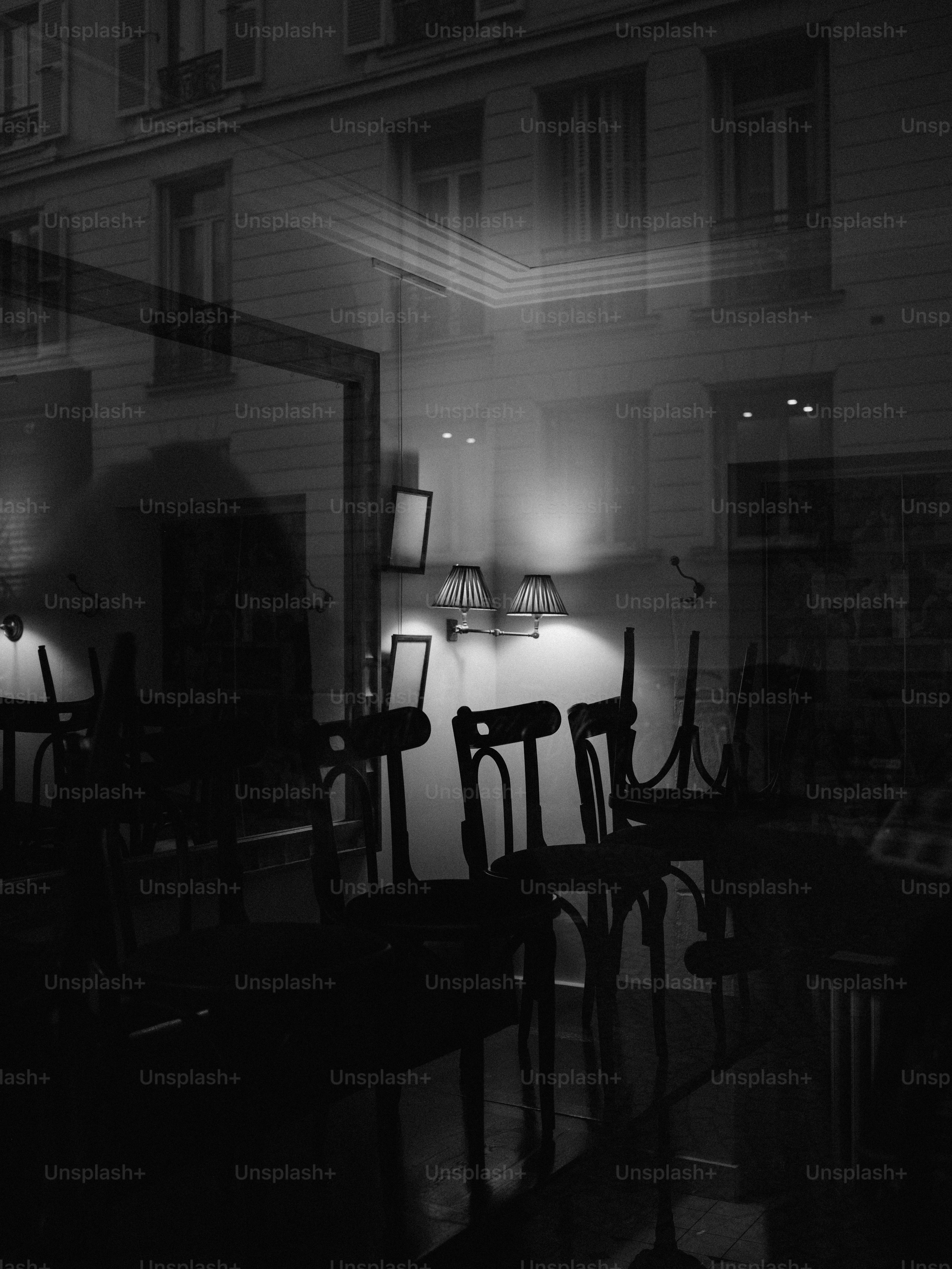Empty chairs and tables reflected in a window at night