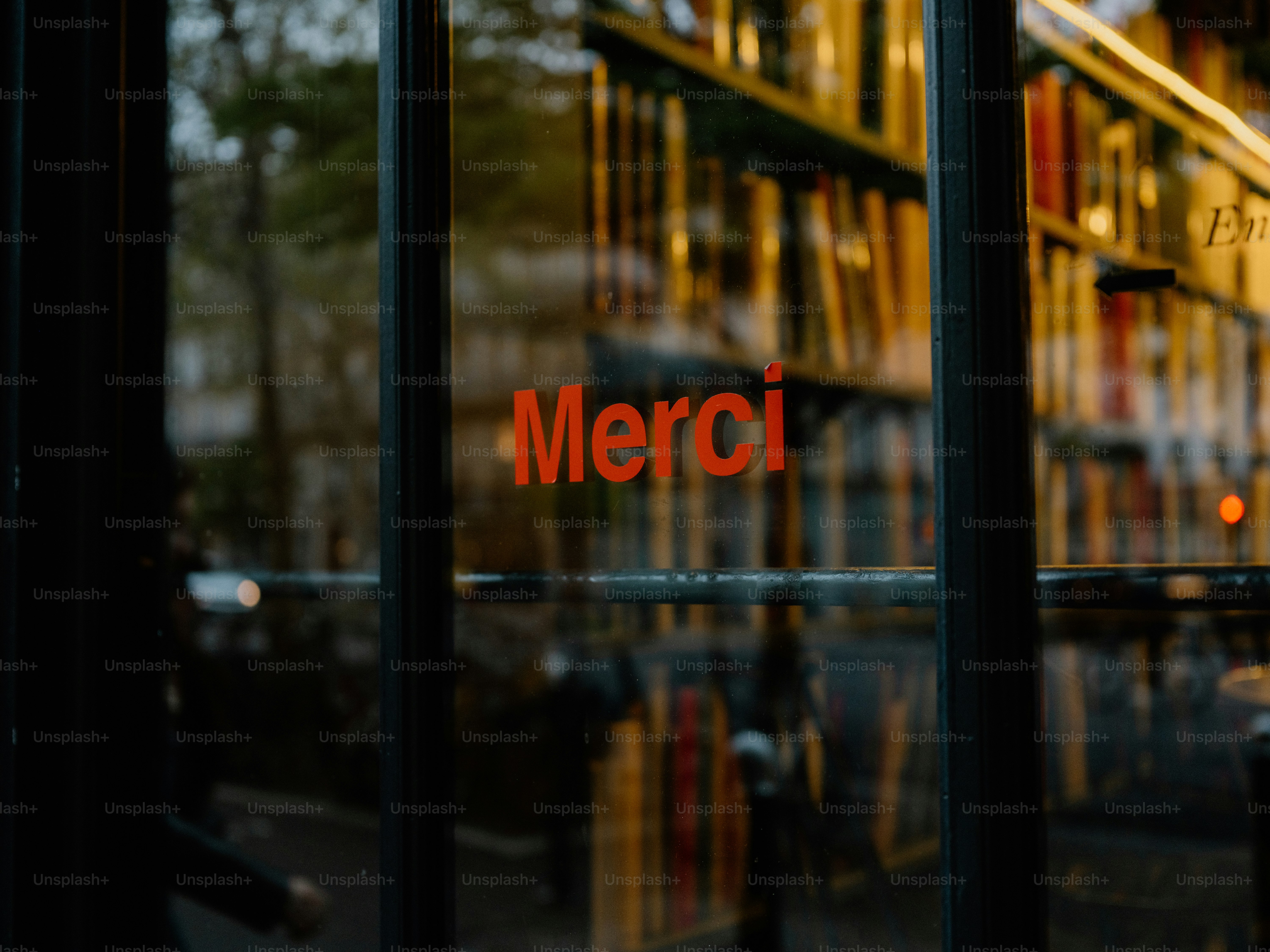 Red "merci" sign reflected in a window