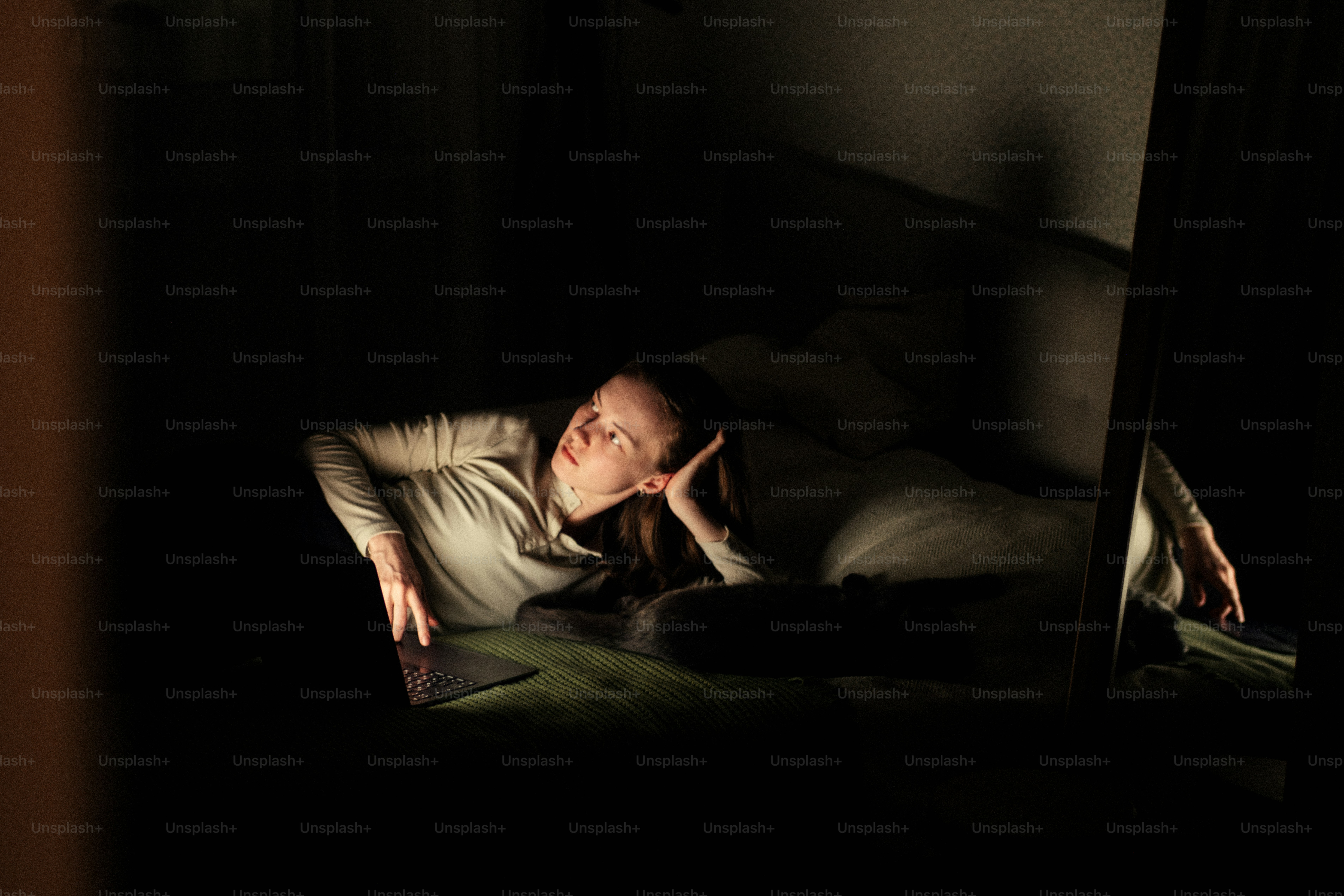 Frau liegt da und schaut auf einen Laptop-Bildschirm