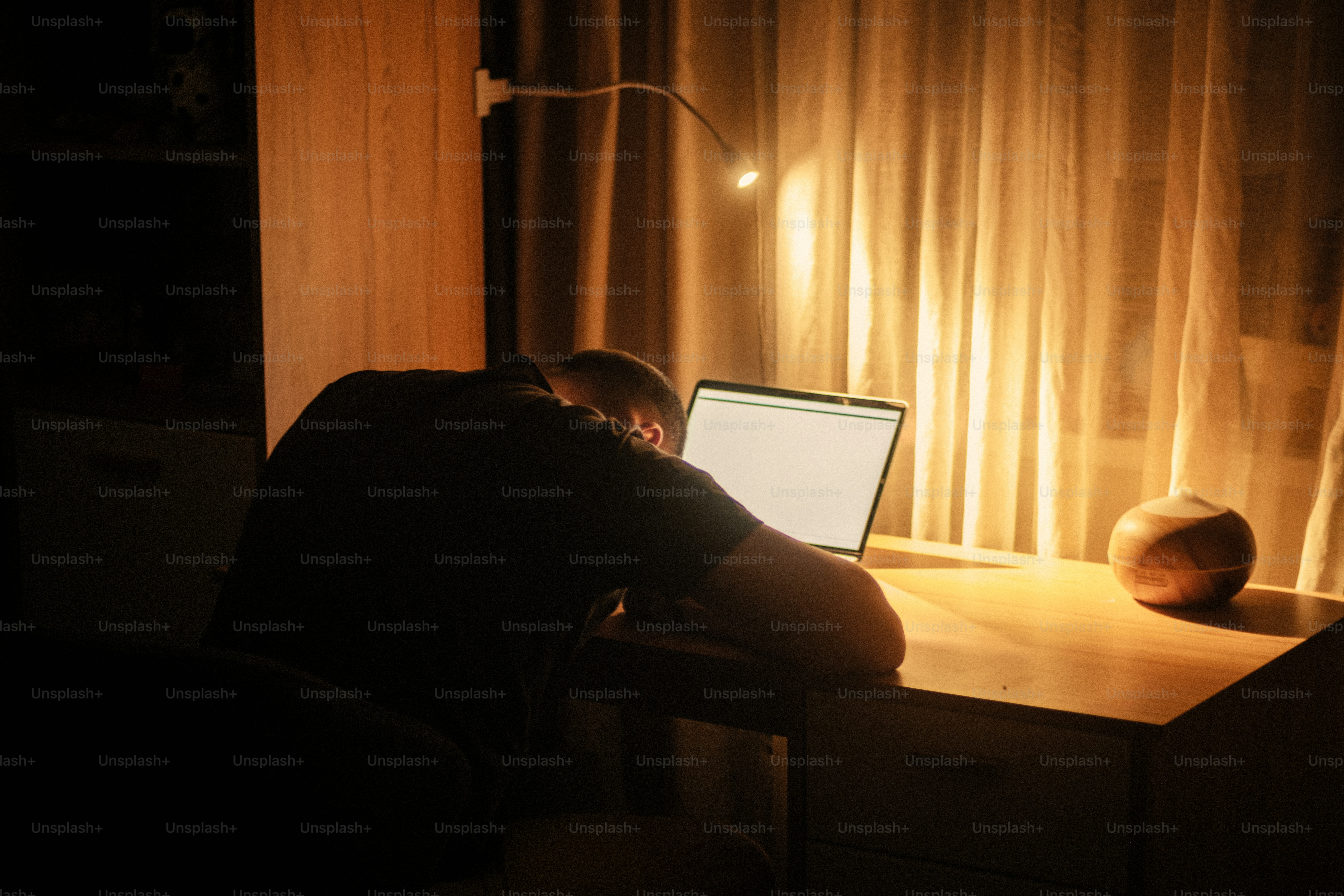 Person, die an einem Schreibtisch mit einem Laptop schläft.