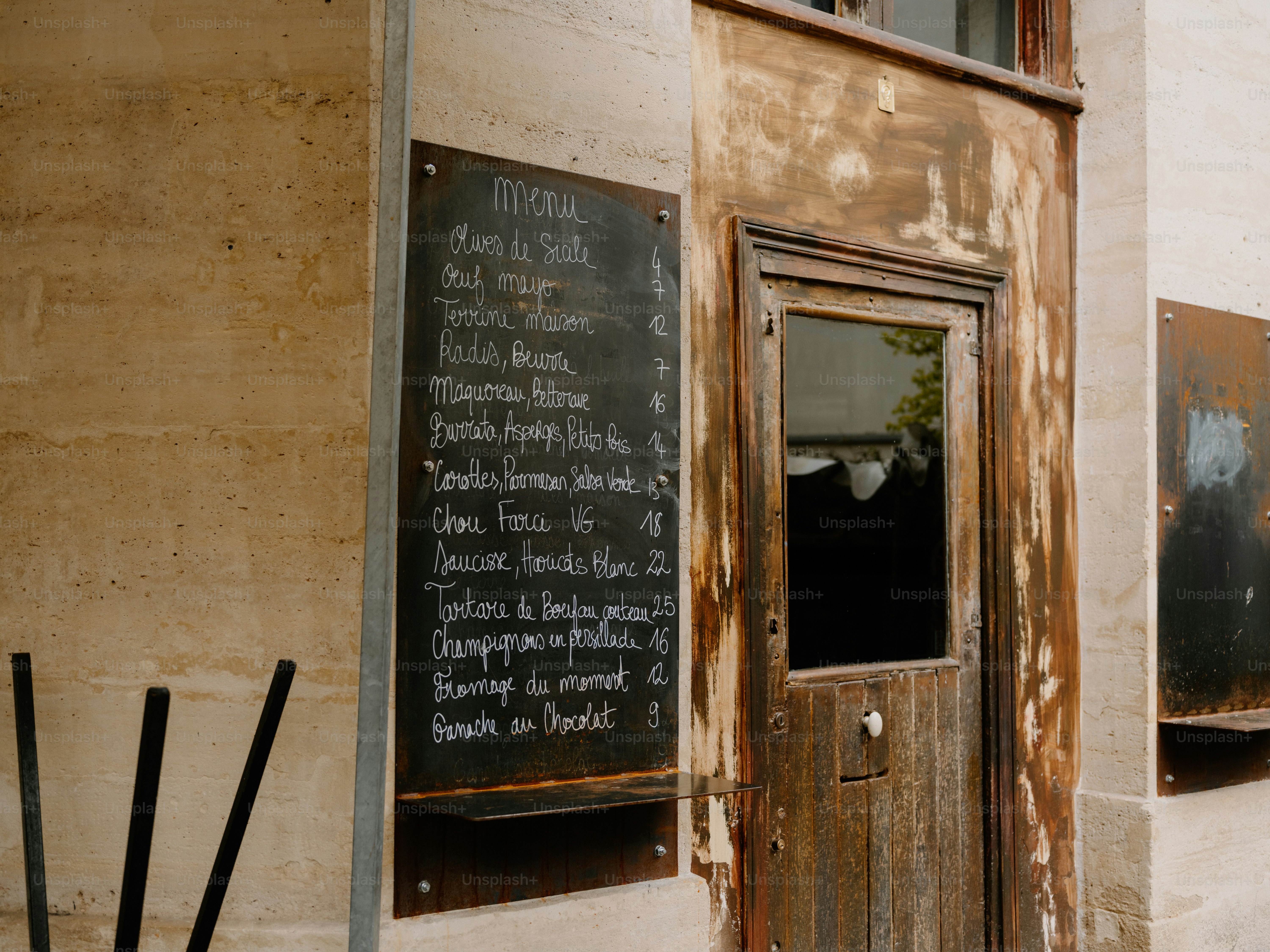 A weathered wooden door with a chalk menu board.