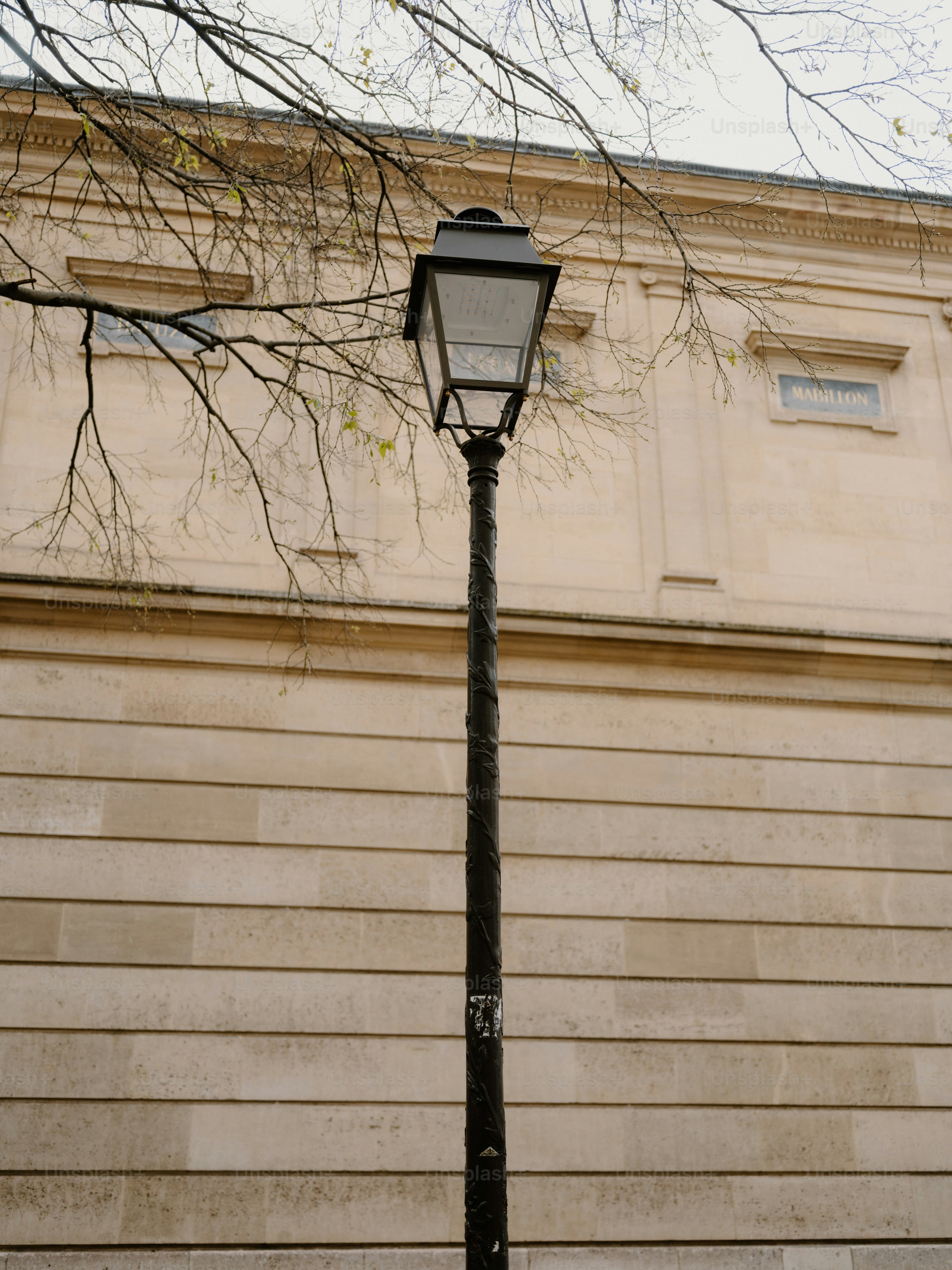 Un lampadaire orné se dresse devant un bâtiment en pierre.