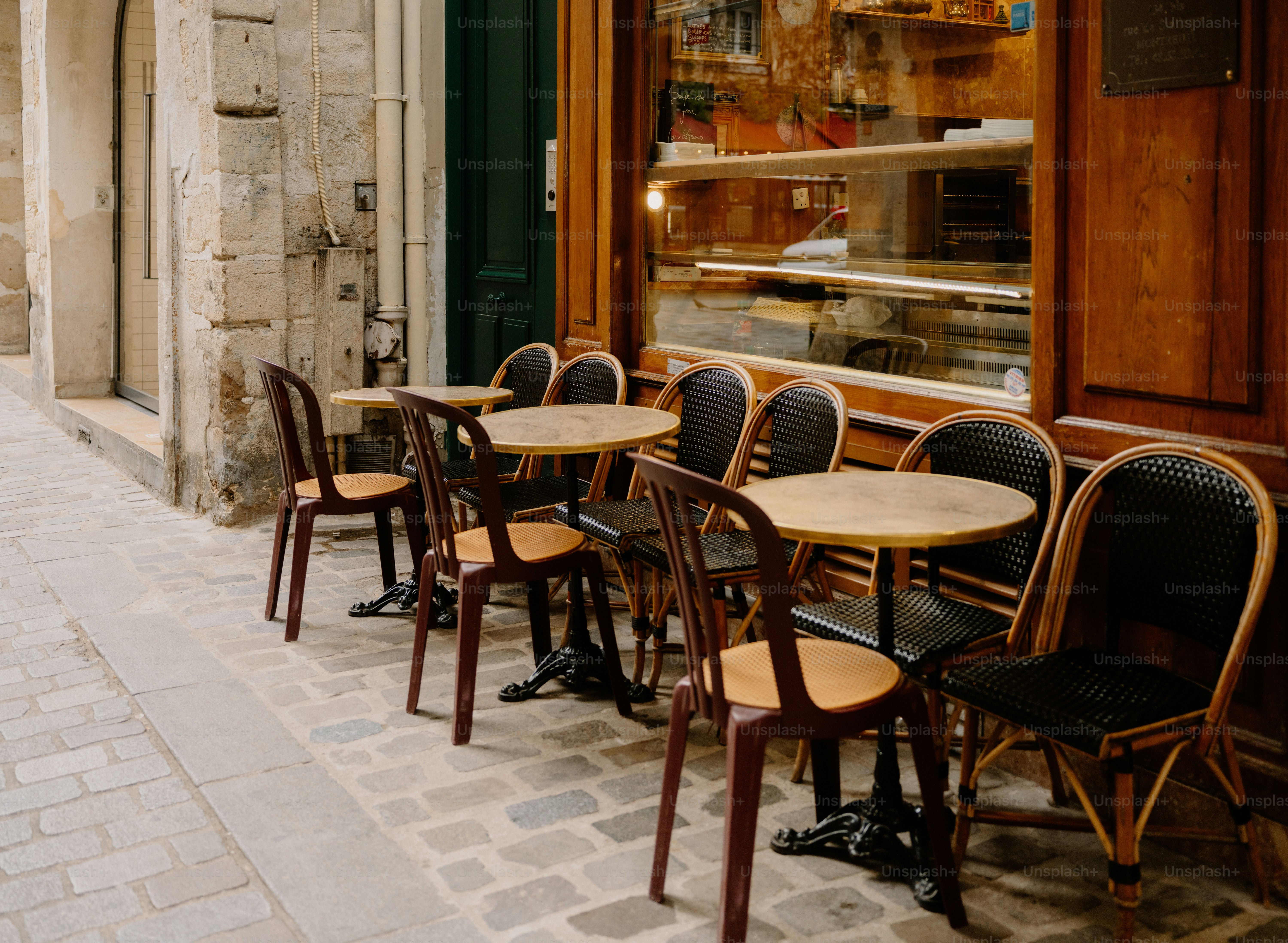 Empty cafe tables and chairs on cobblestone street