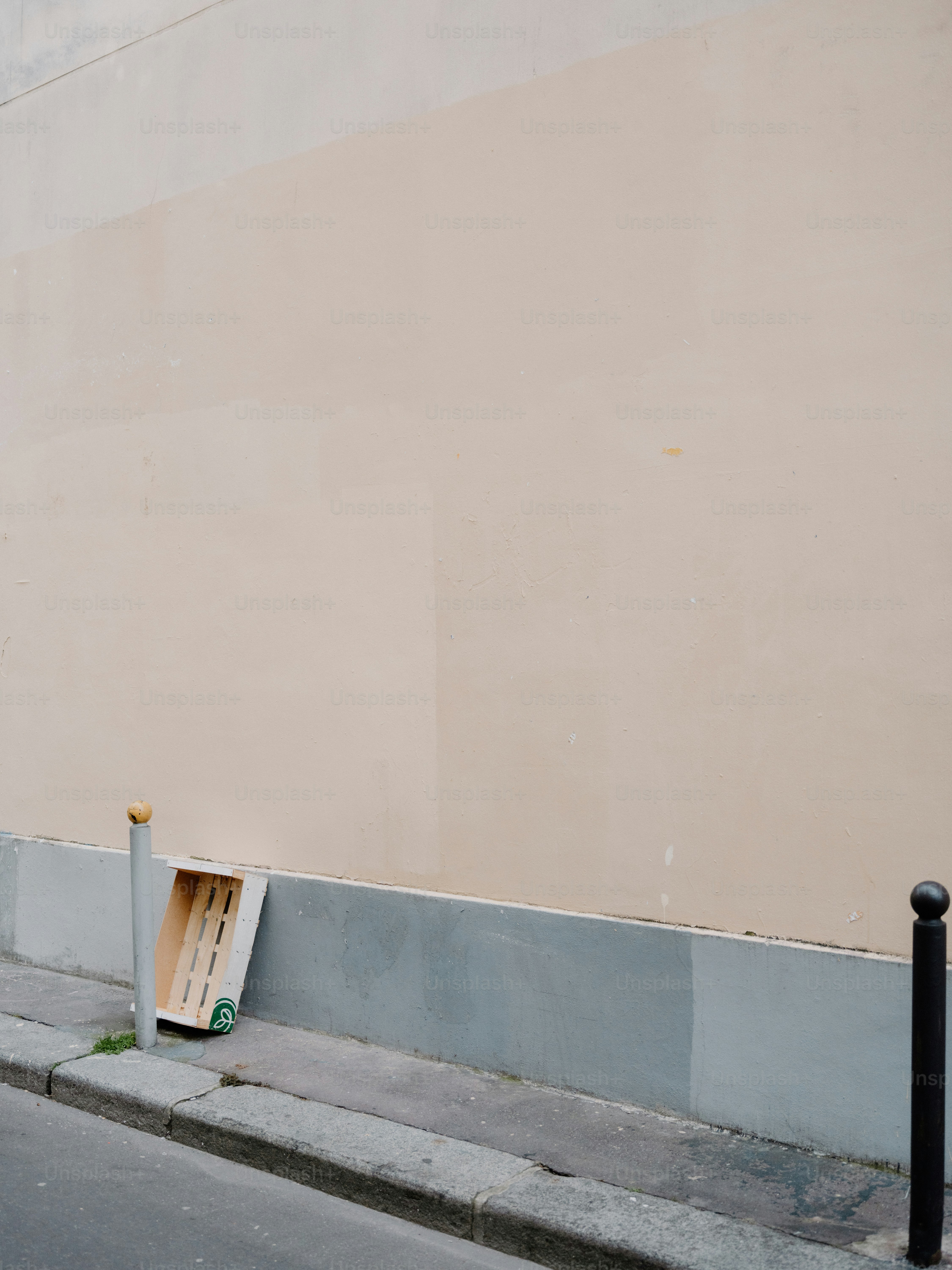 Una caja de madera vacía descansa contra una pared pálida.
