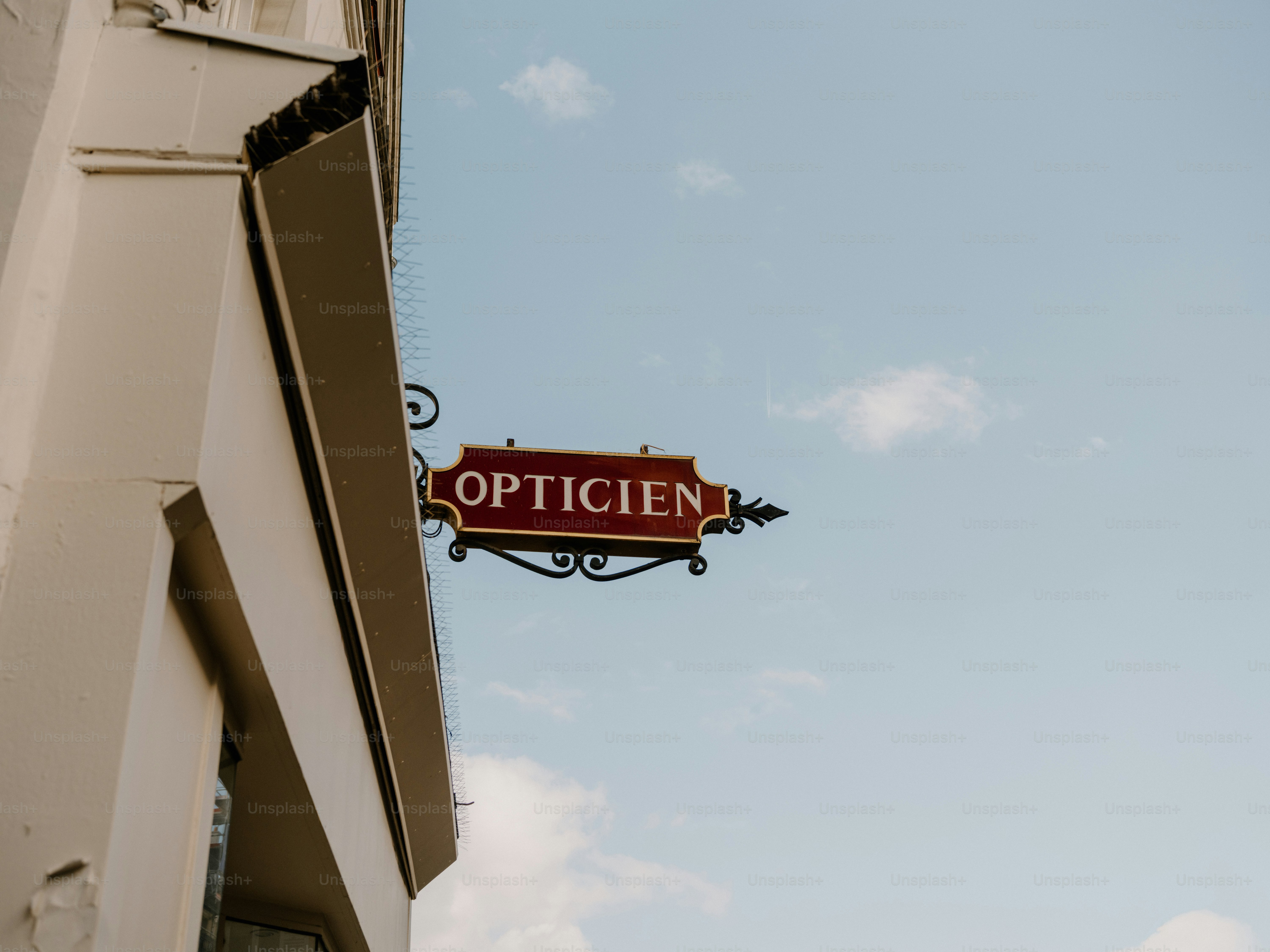 Red optician sign hanging from building photo – Business Image on Unsplash