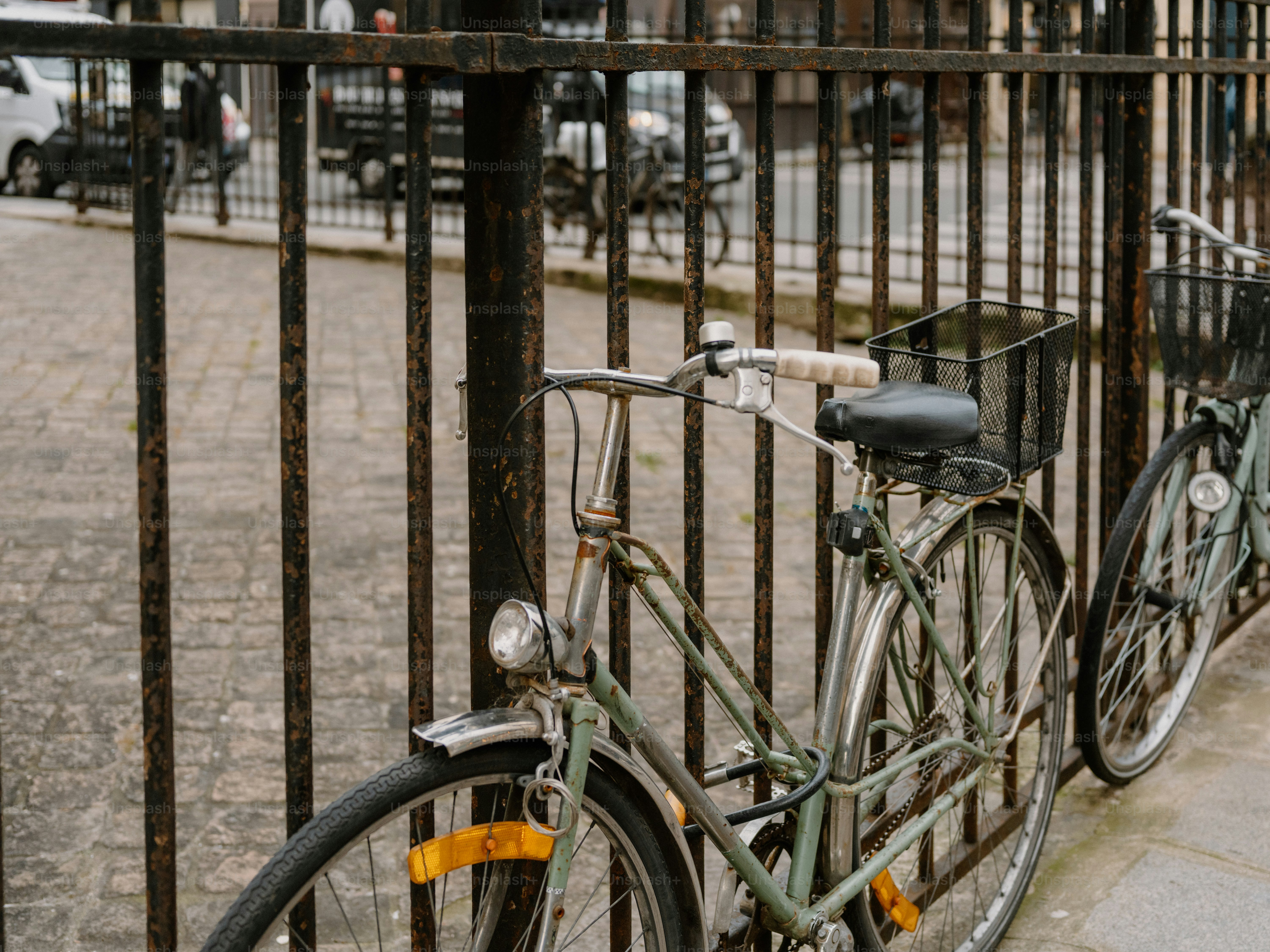 Two bicycles parked behind a metal fence.