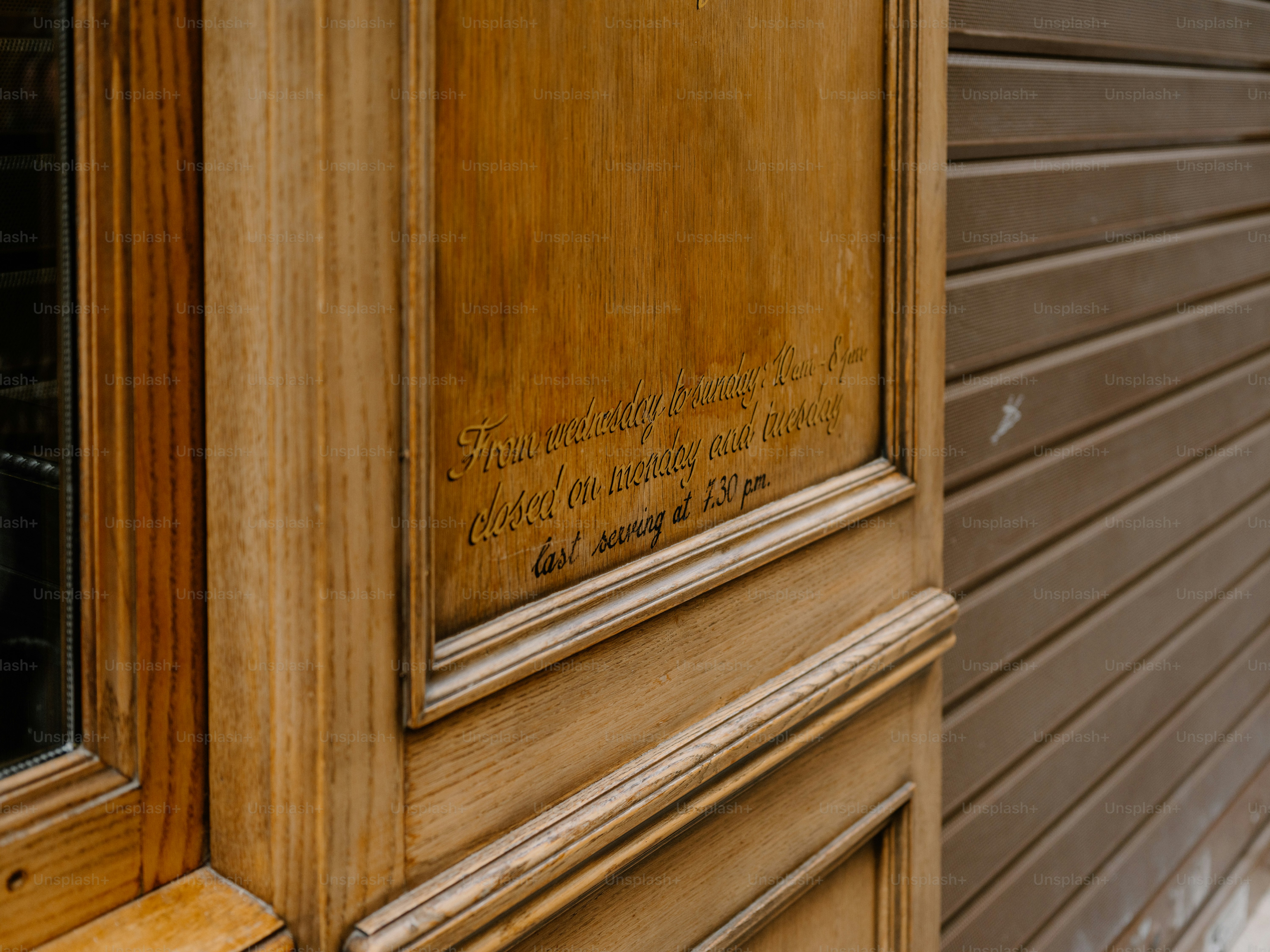 Close-up of weathered wooden door with faint inscription.