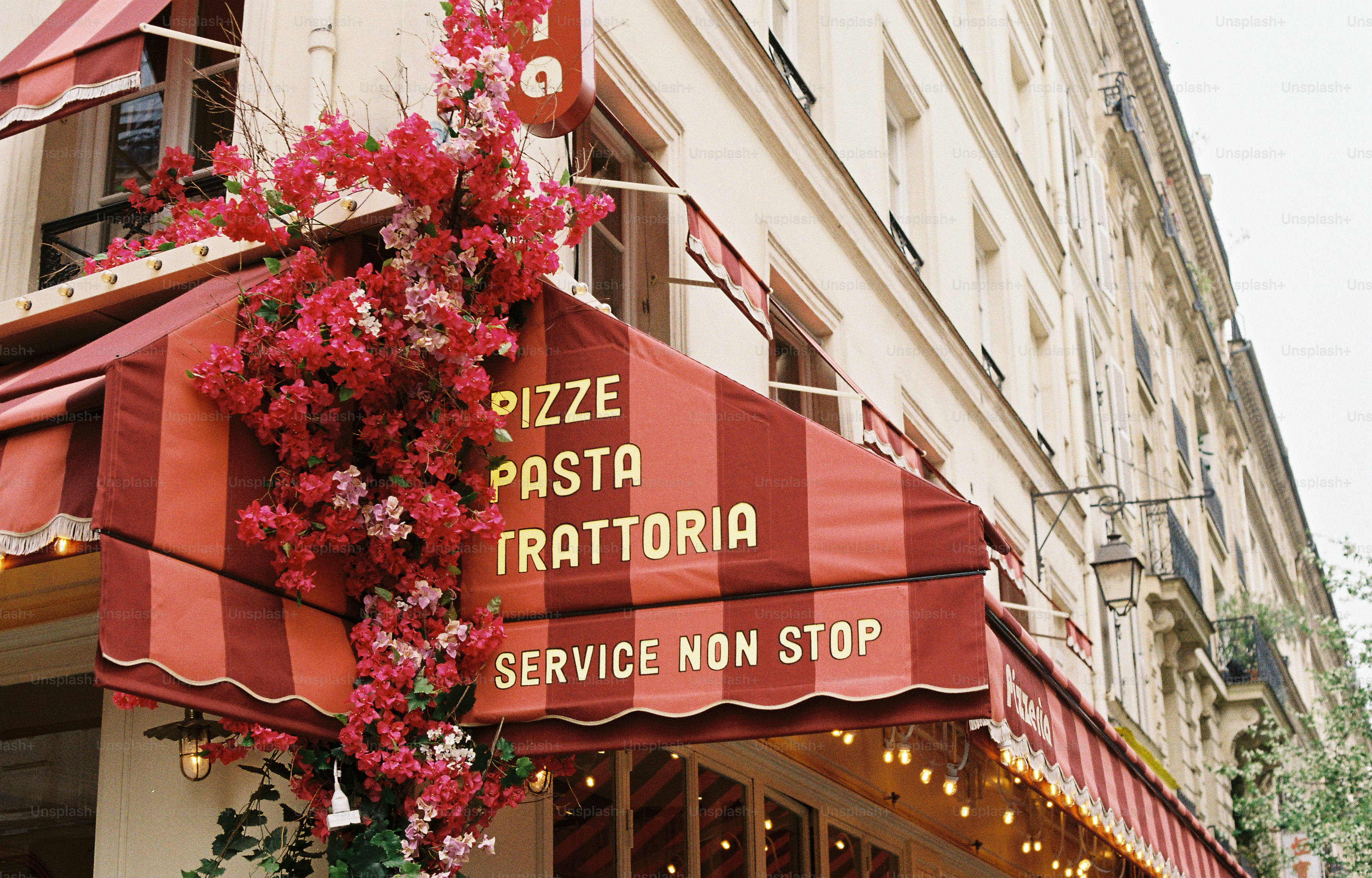 Tenda a strisce rosse di una trattoria con fiori.