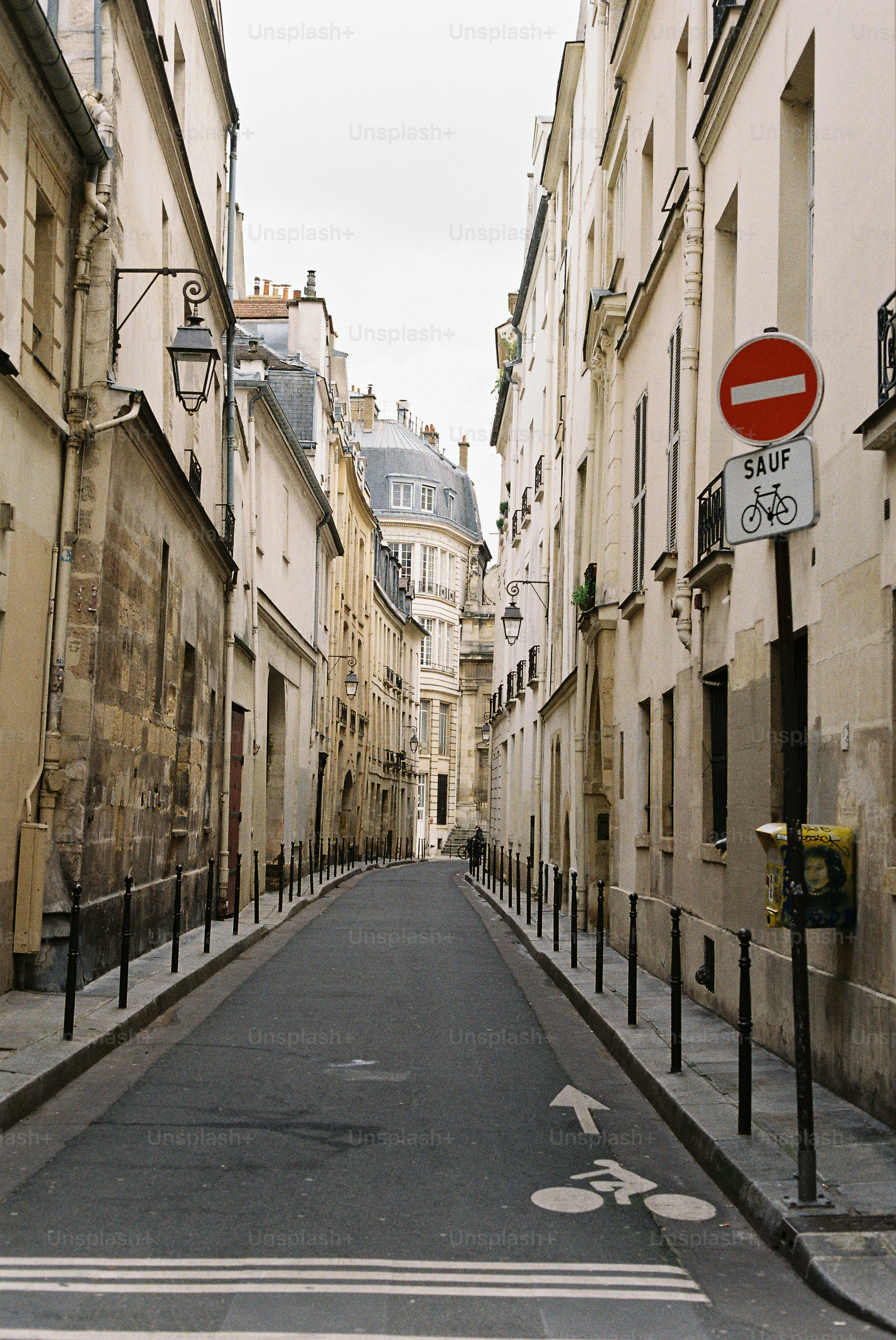 Rua estreita parisiense com prédios e uma ciclovia.