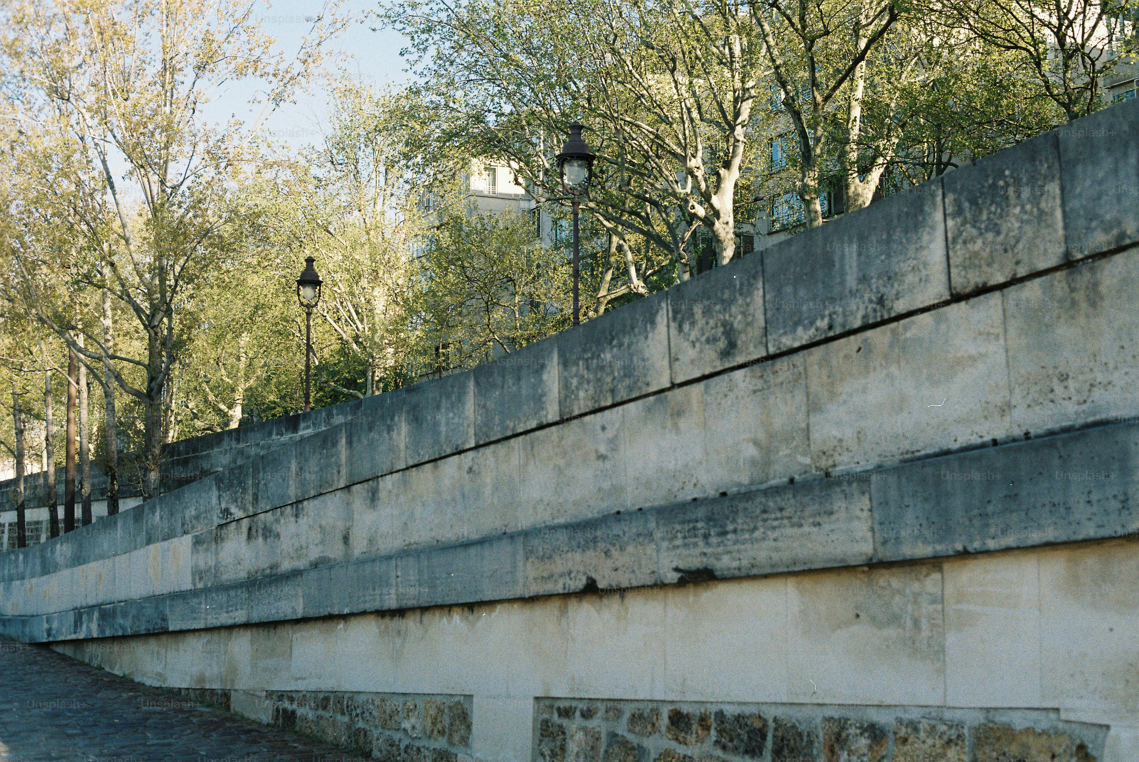 Terraplén de piedra con árboles y farolas arriba