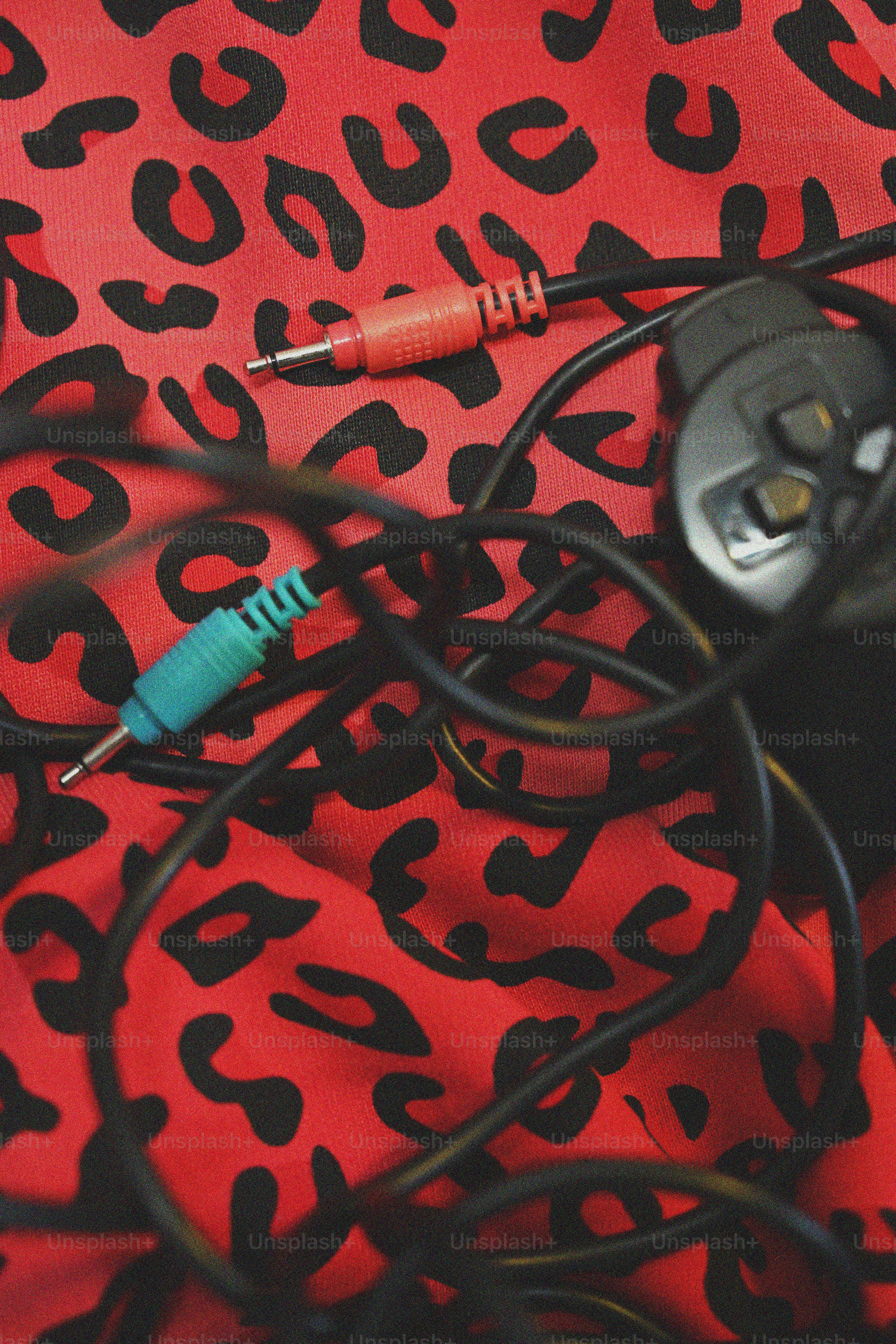 Kabel kusut dan pengontrol game pada cetakan macan tutul merah