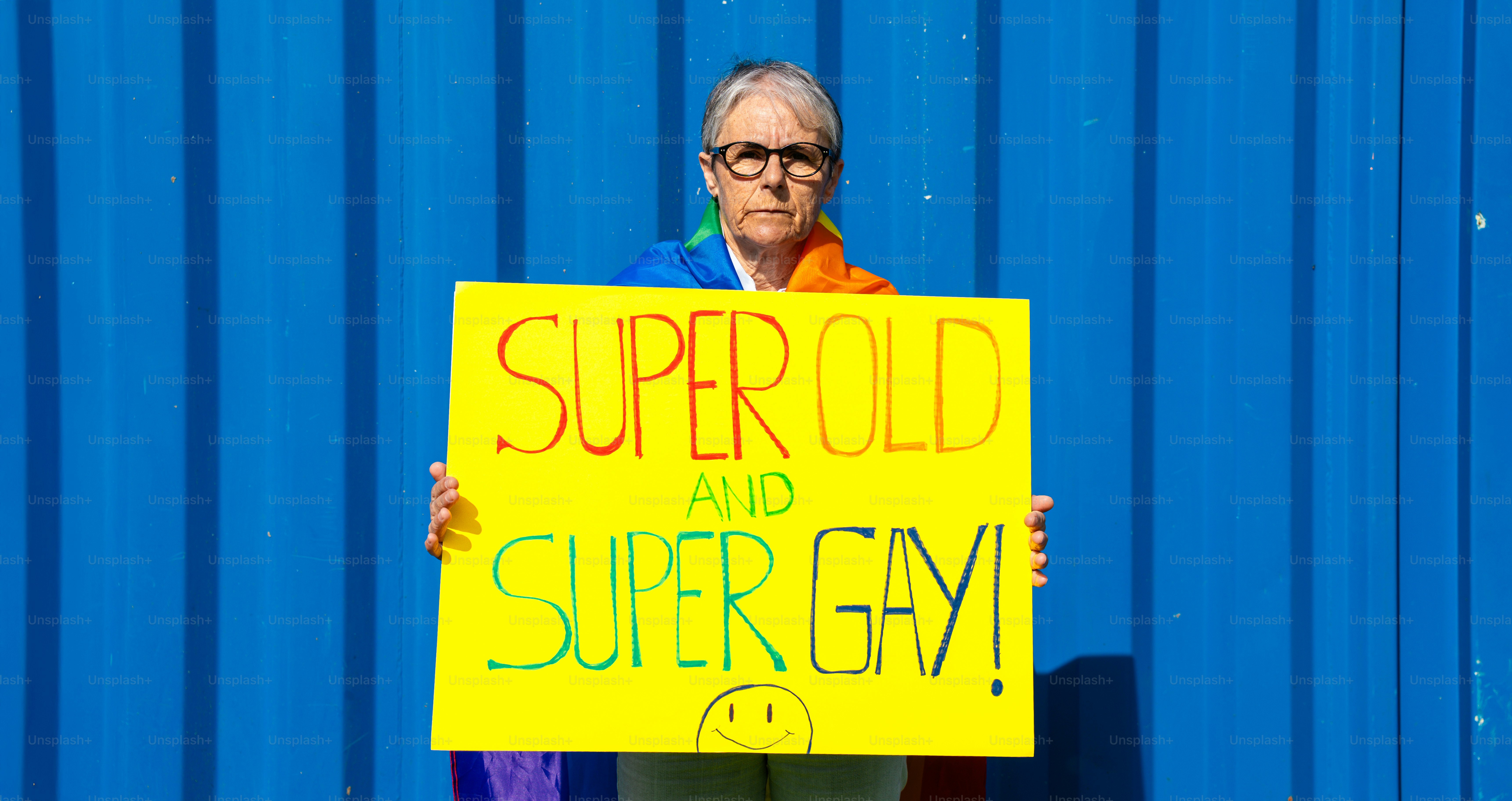 Une personne tient une pancarte sur lequel il est écrit « super vieux et super gay ! »