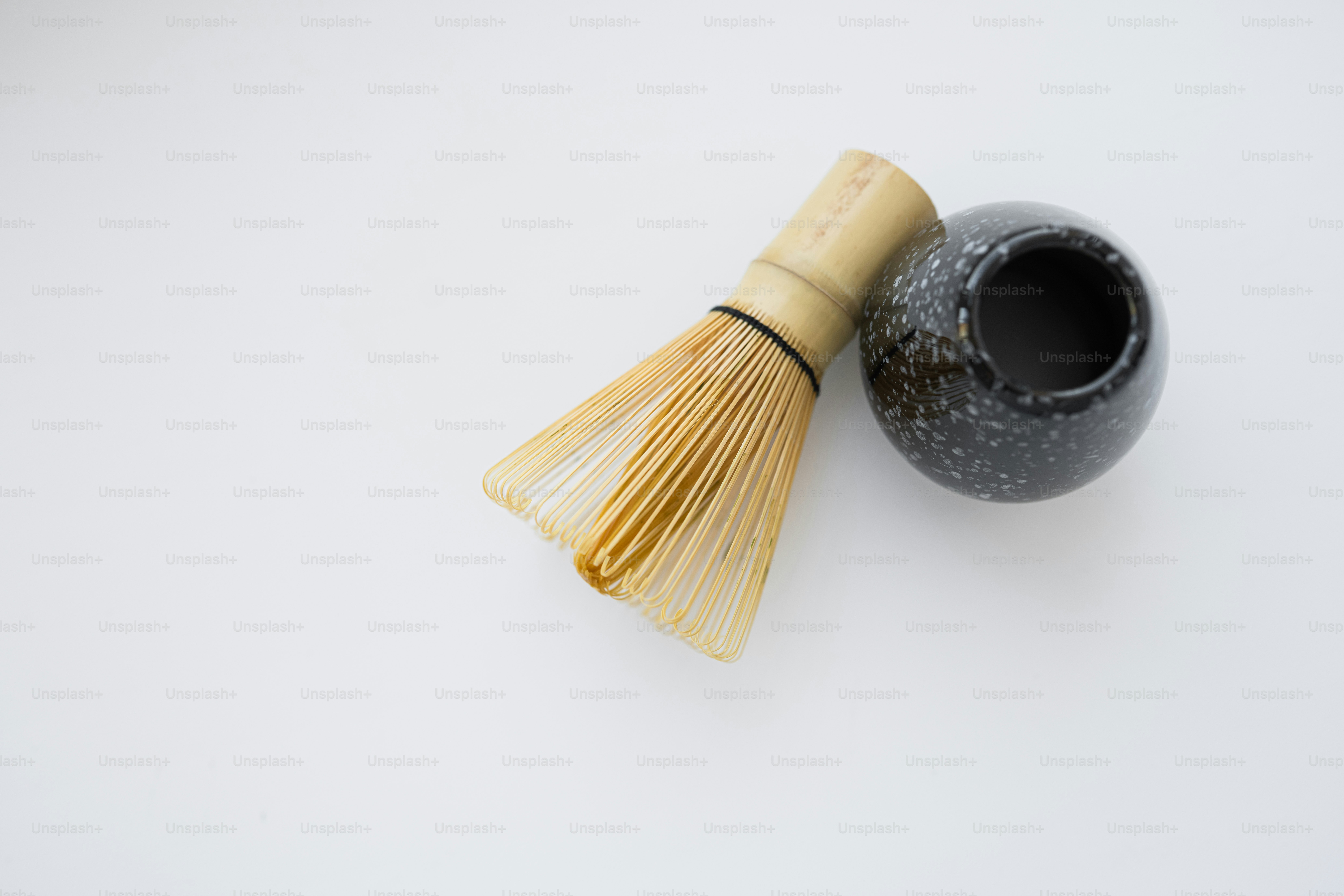 Bamboo matcha whisk and ceramic bowl on white background
