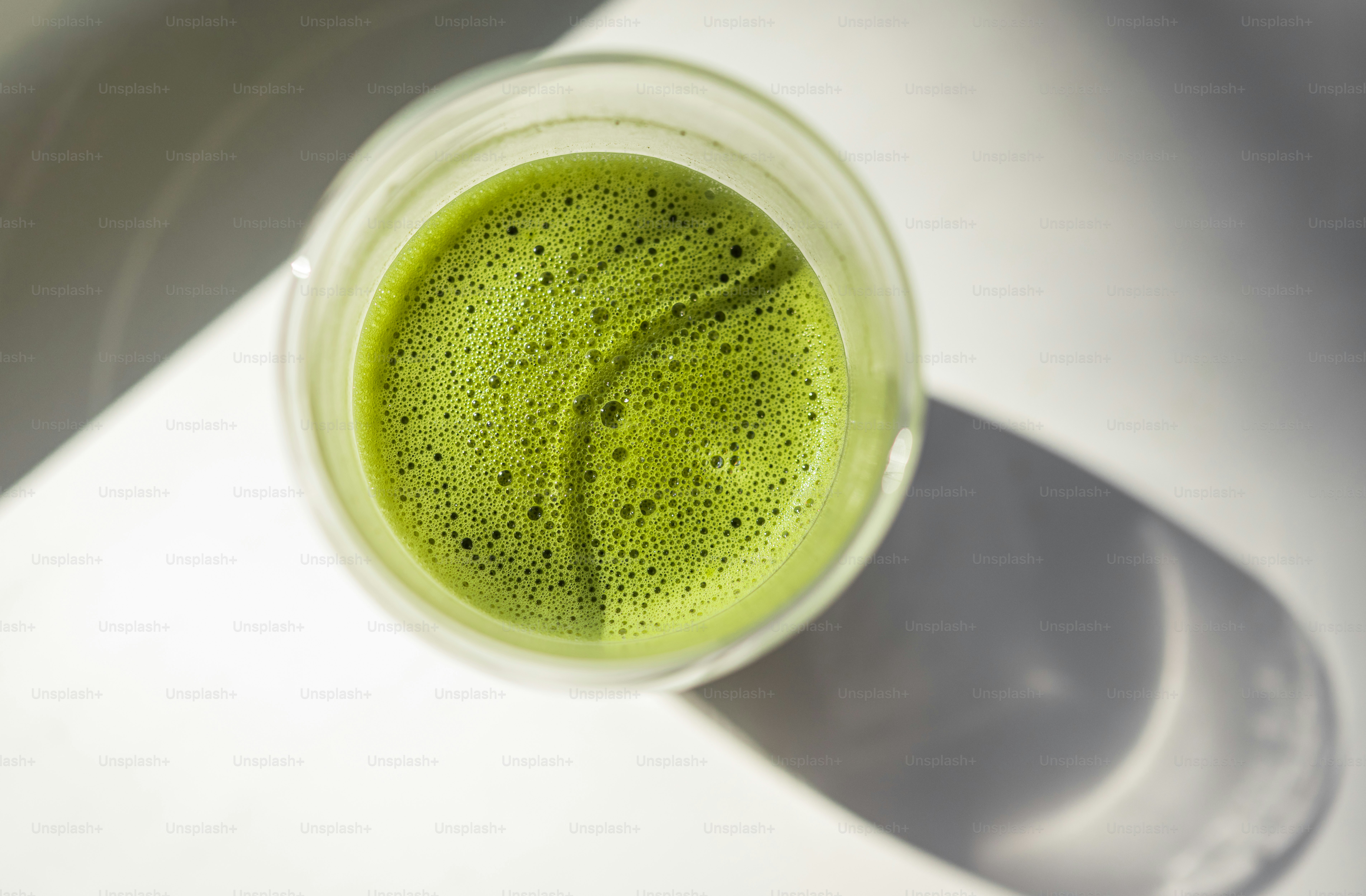 A frothy green matcha tea in a clear glass.