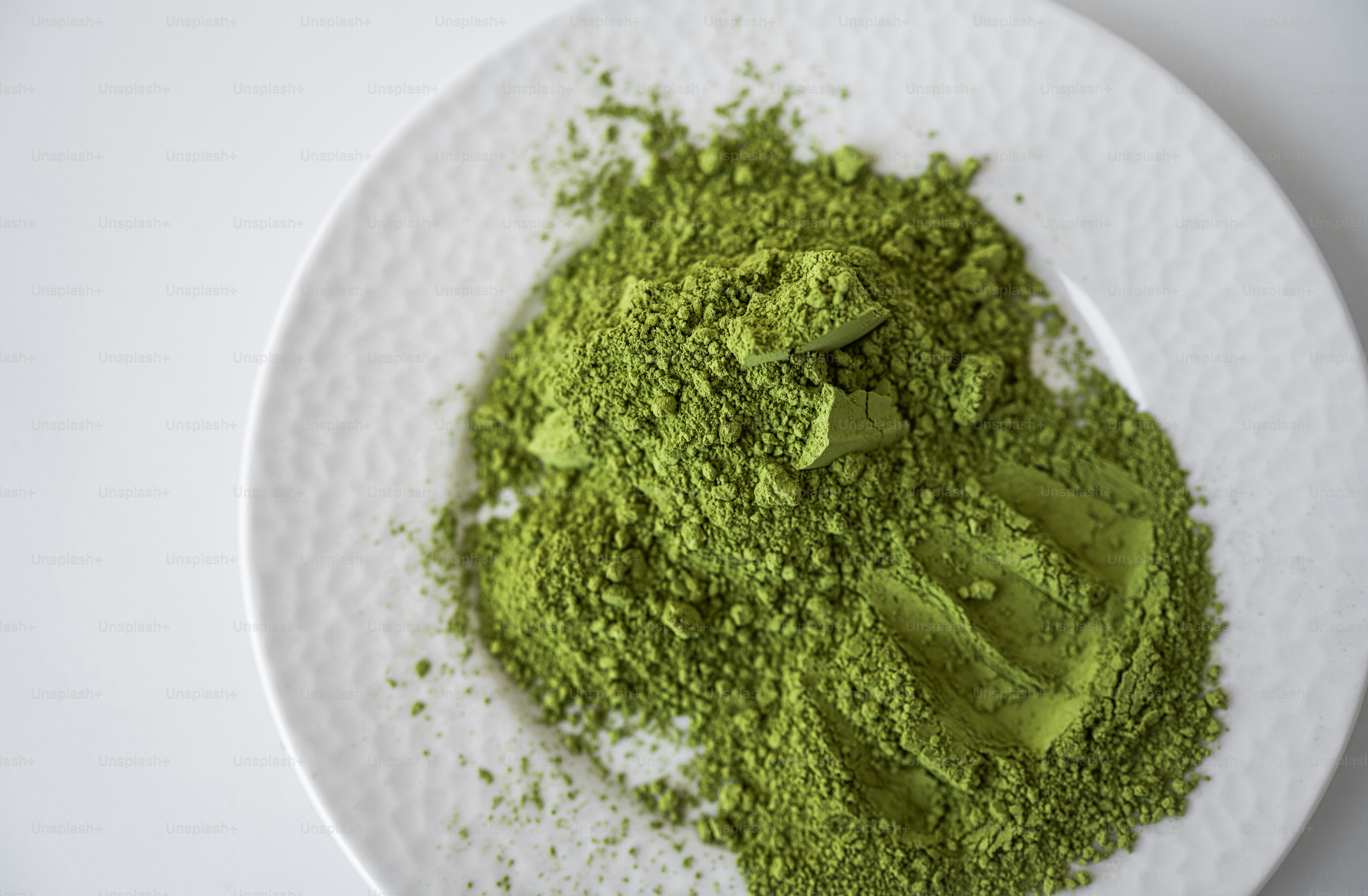 A pile of green matcha powder on a white plate.